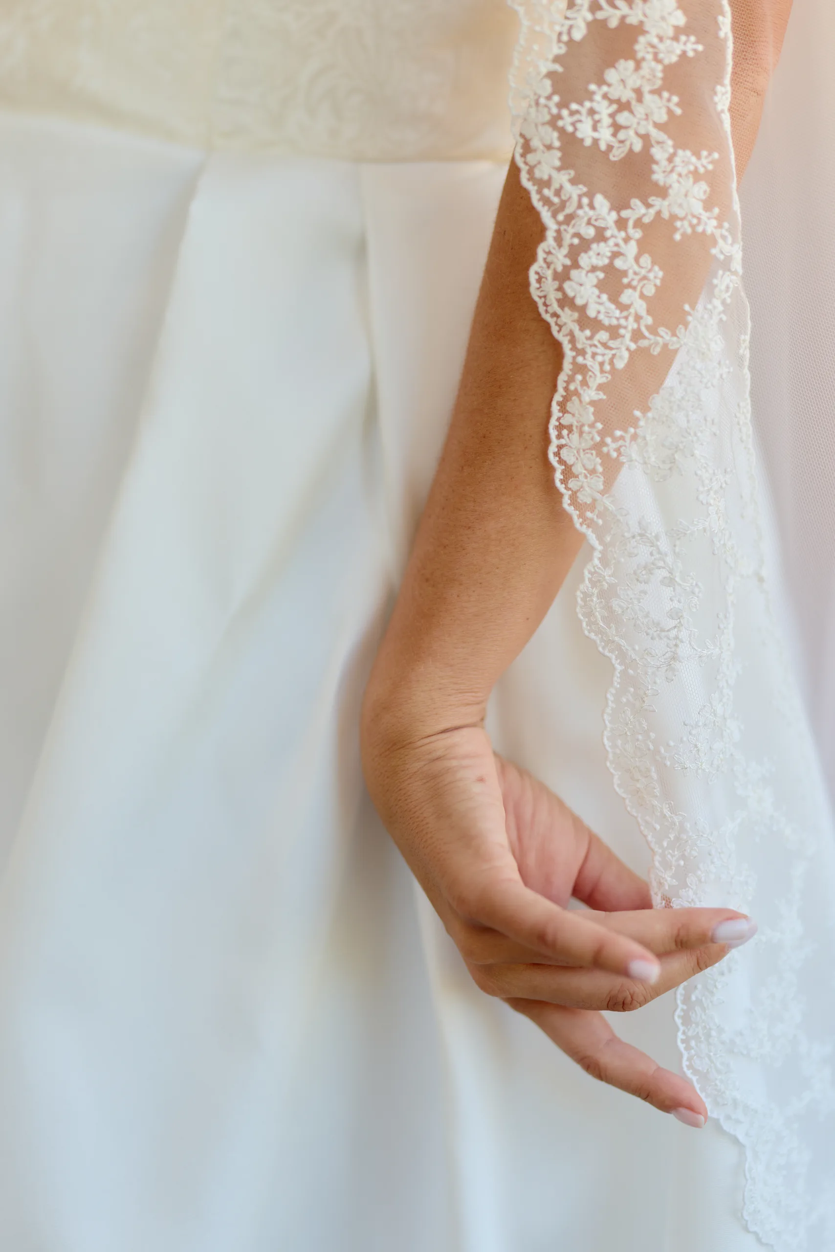 Détail de la dentelle et des mains de la mariée