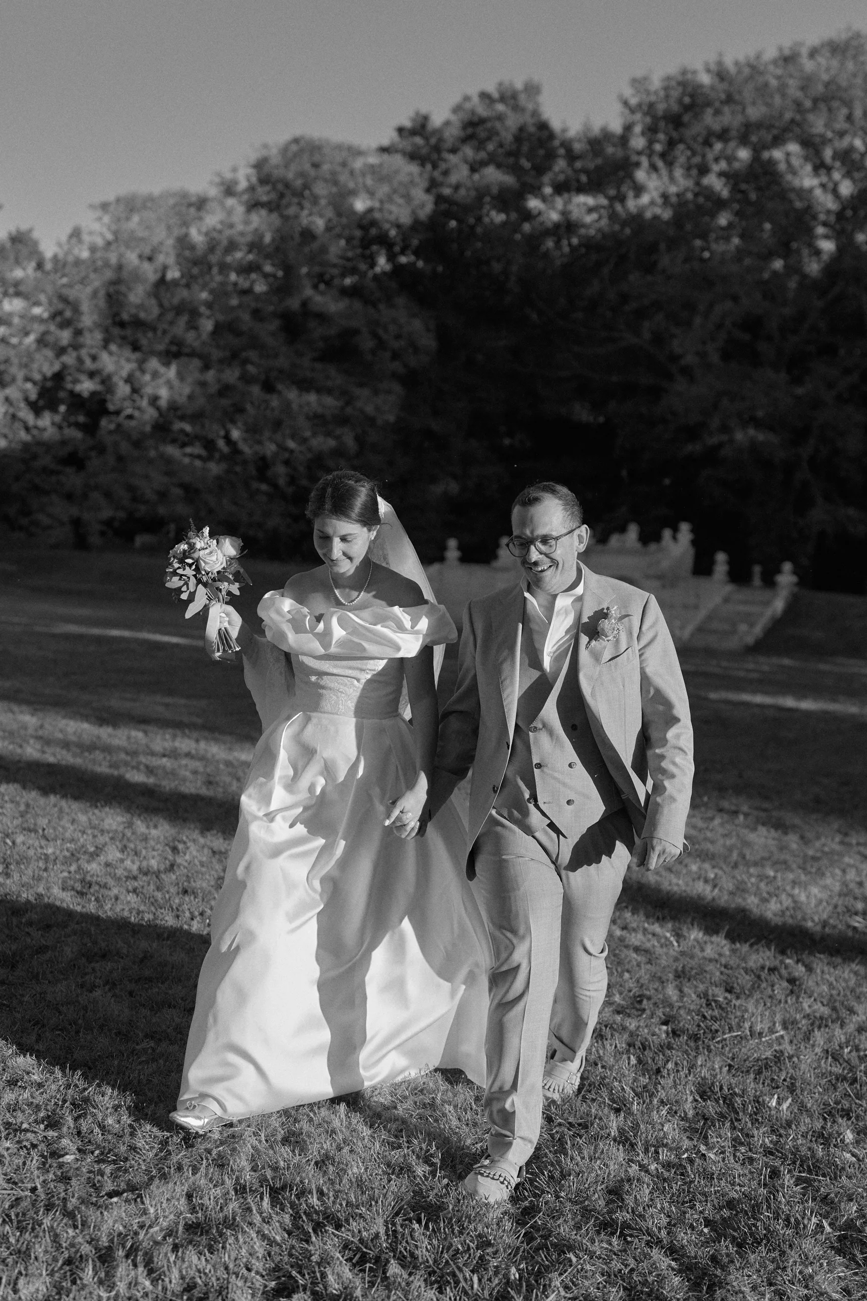 Les mariés marchent dans le parc, en noir et blanc