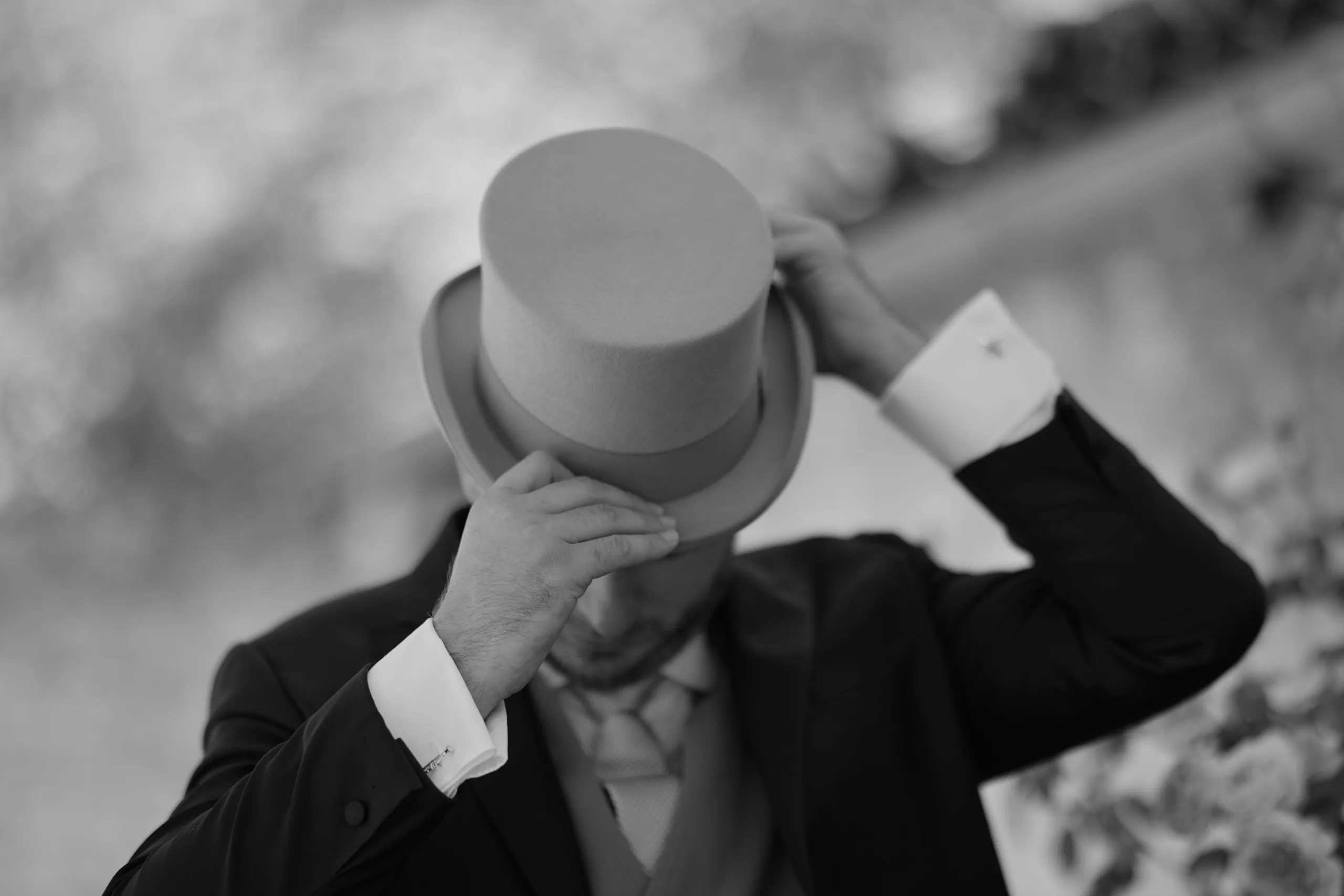 Homme ajustant son haut-de-forme, en noir et blanc