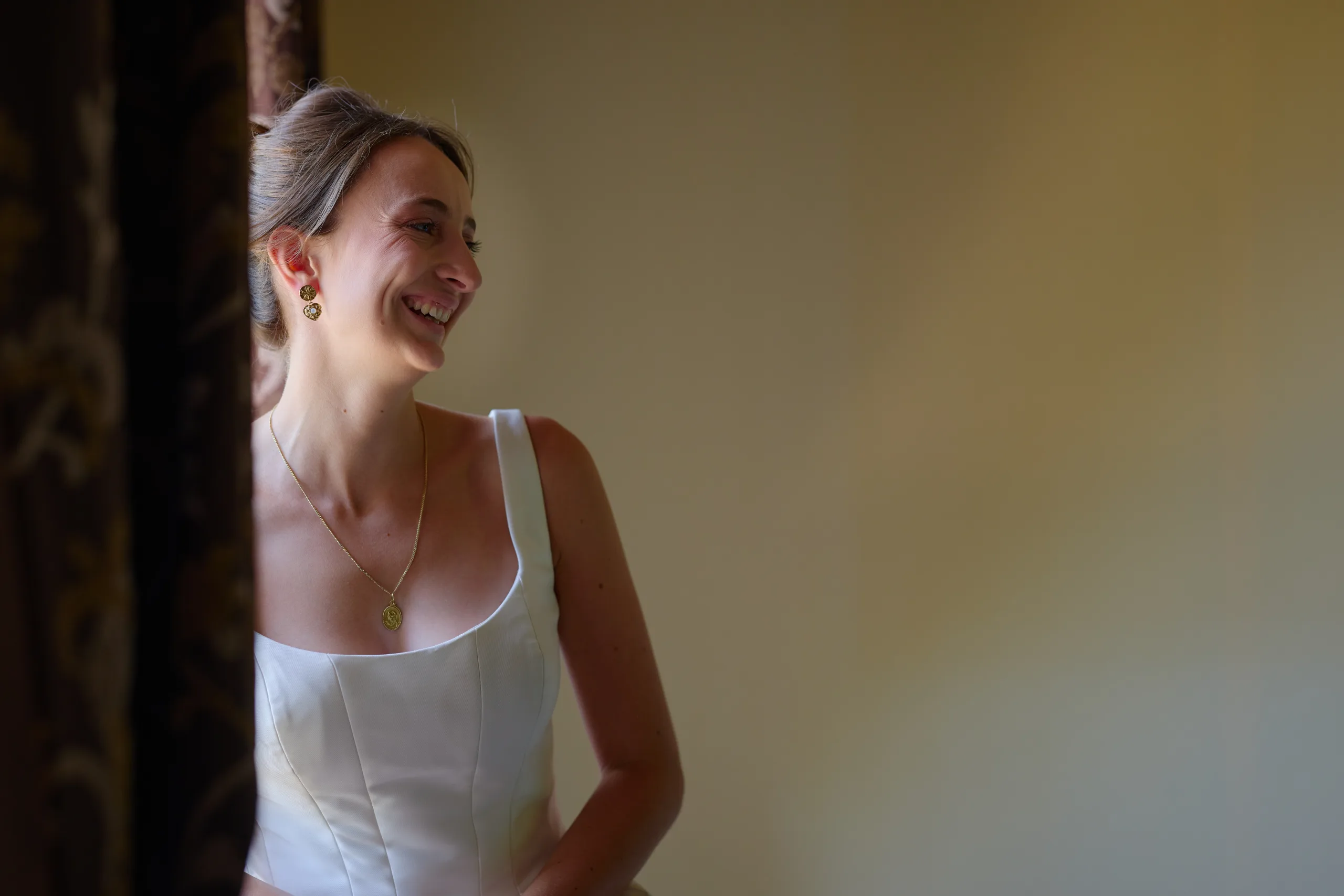 Femme souriante en robe blanche près d’une fenêtre