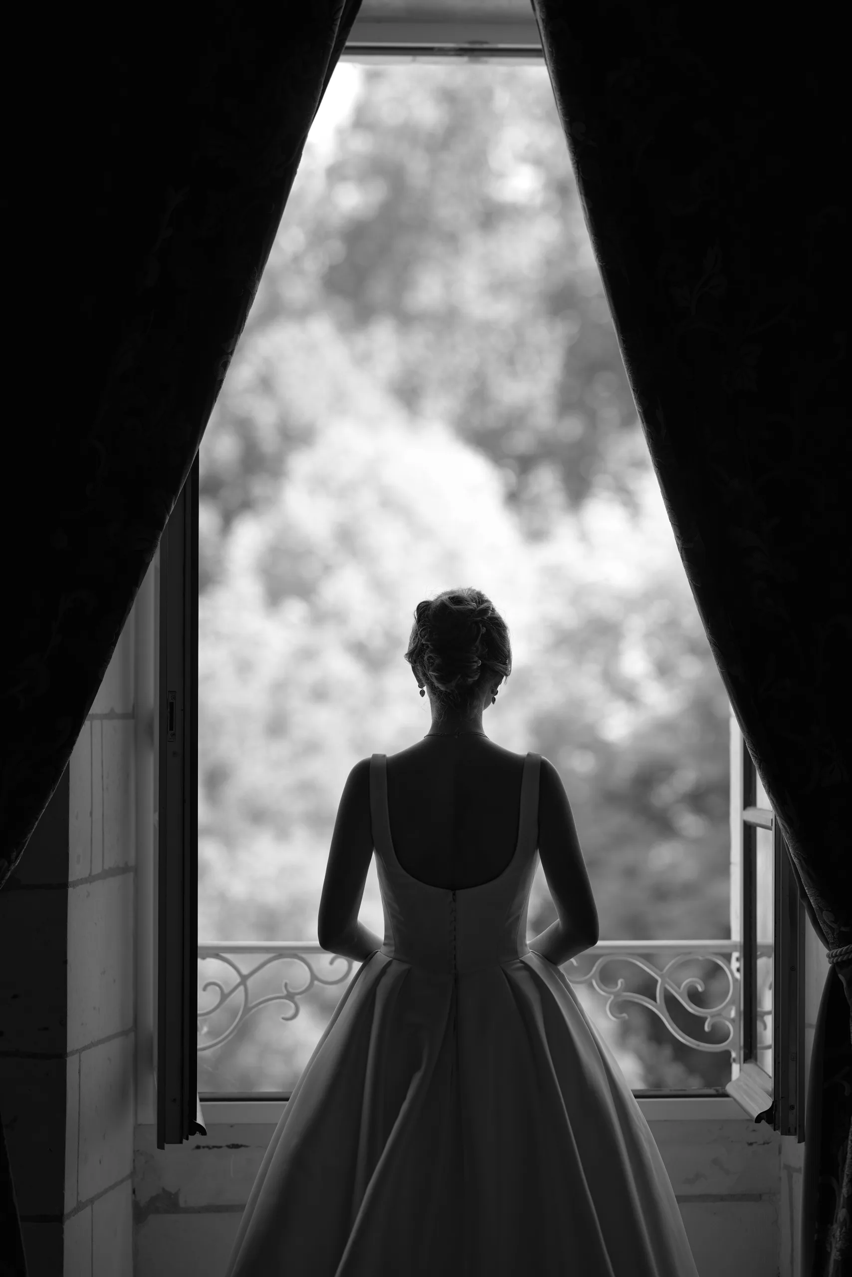 Silhouette d’une femme en robe blanche devant une fenêtre