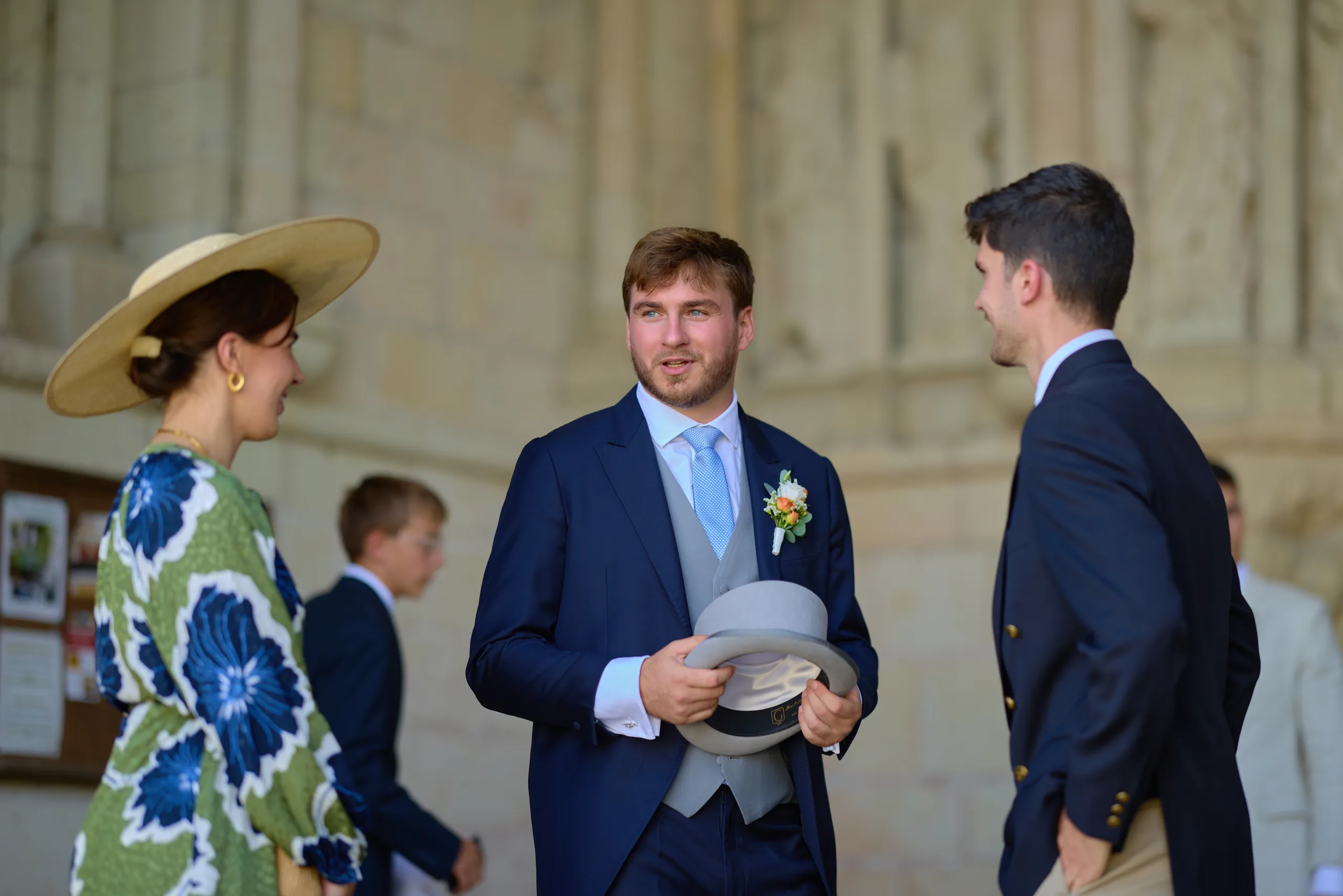 Un homme tient son haut-de-forme devant des invités