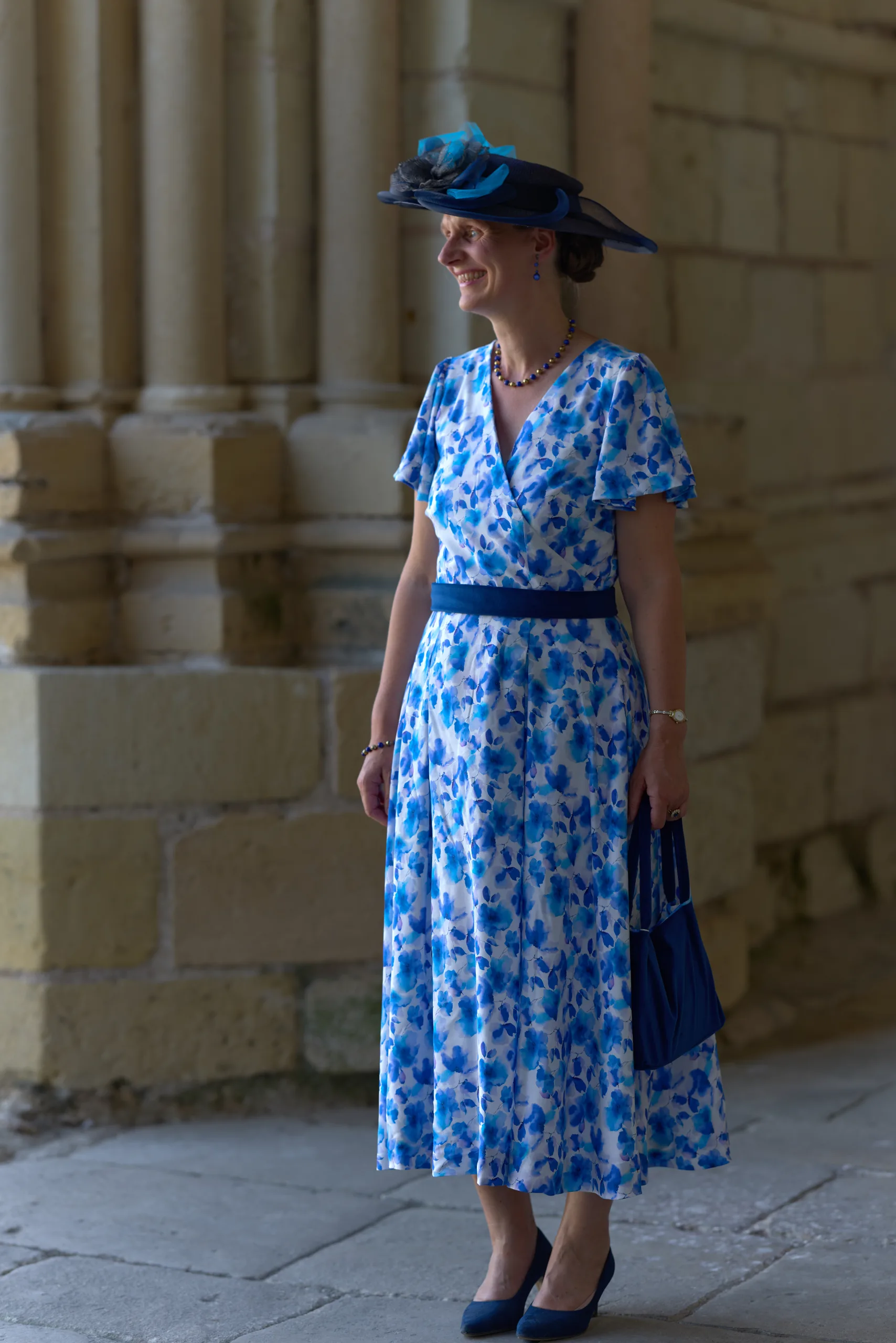 Femme en robe bleue à motifs devant l’église