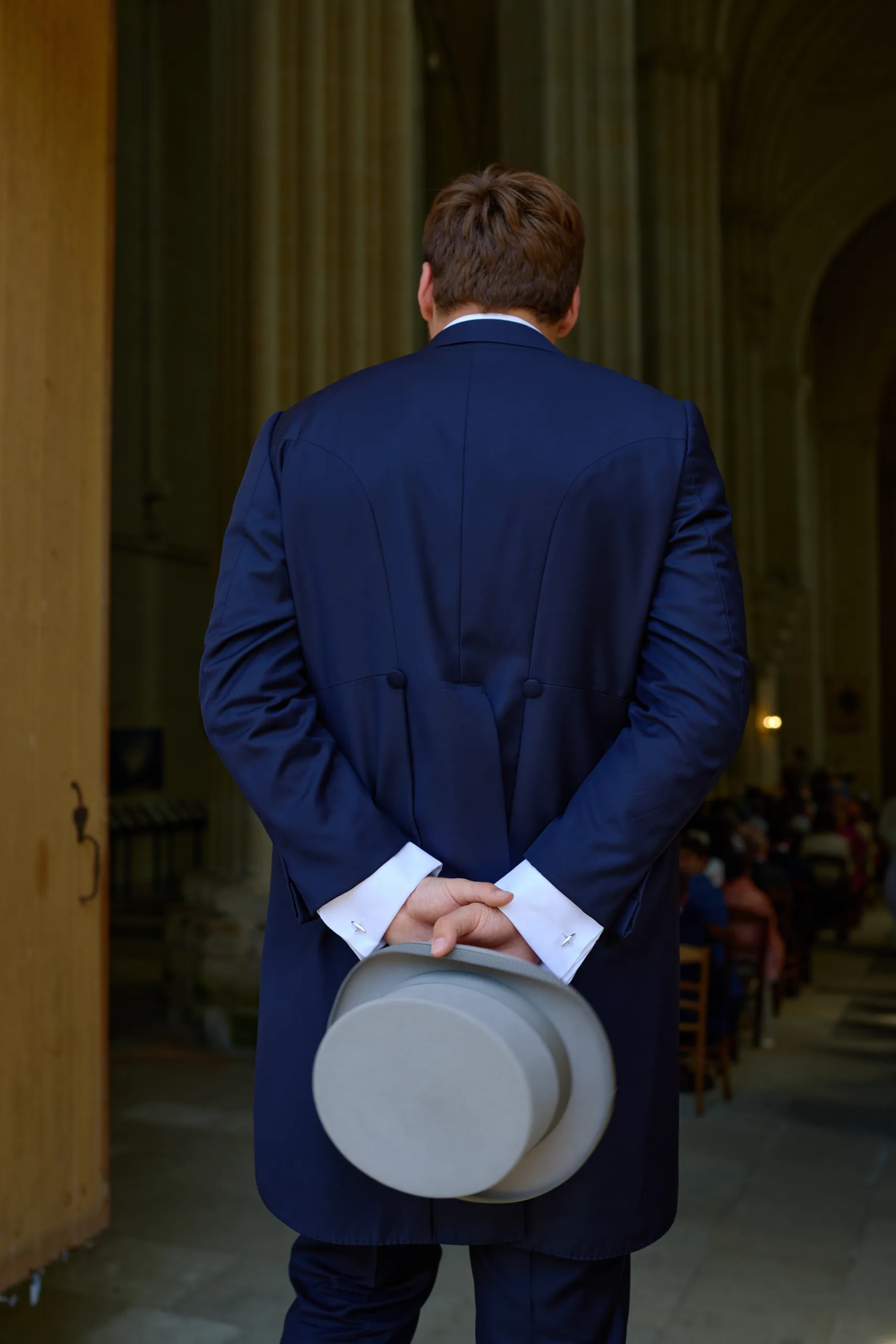 Homme en costume tenant un chapeau derrière son dos