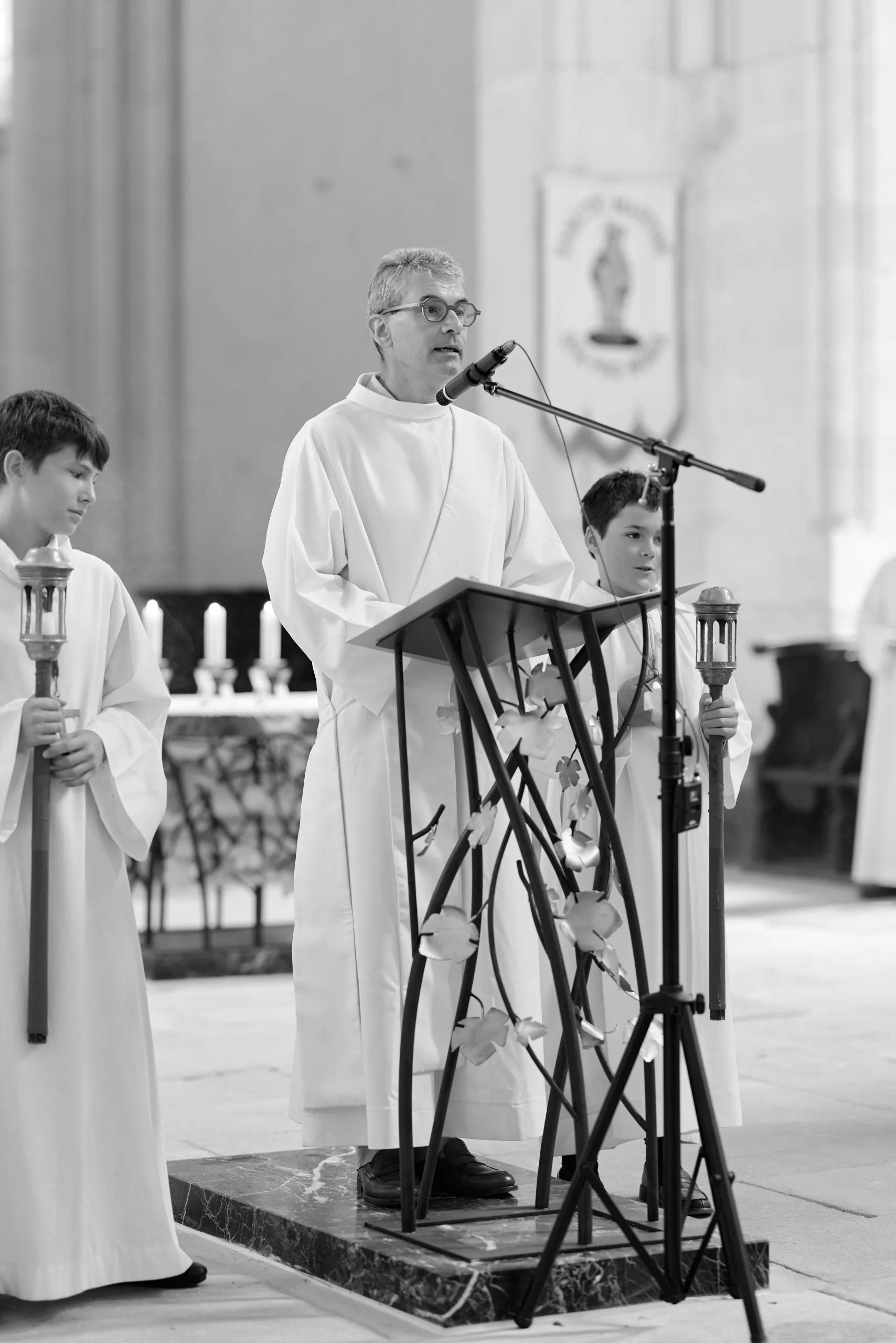 Prêtre s’exprimant au pupitre, en noir et blanc