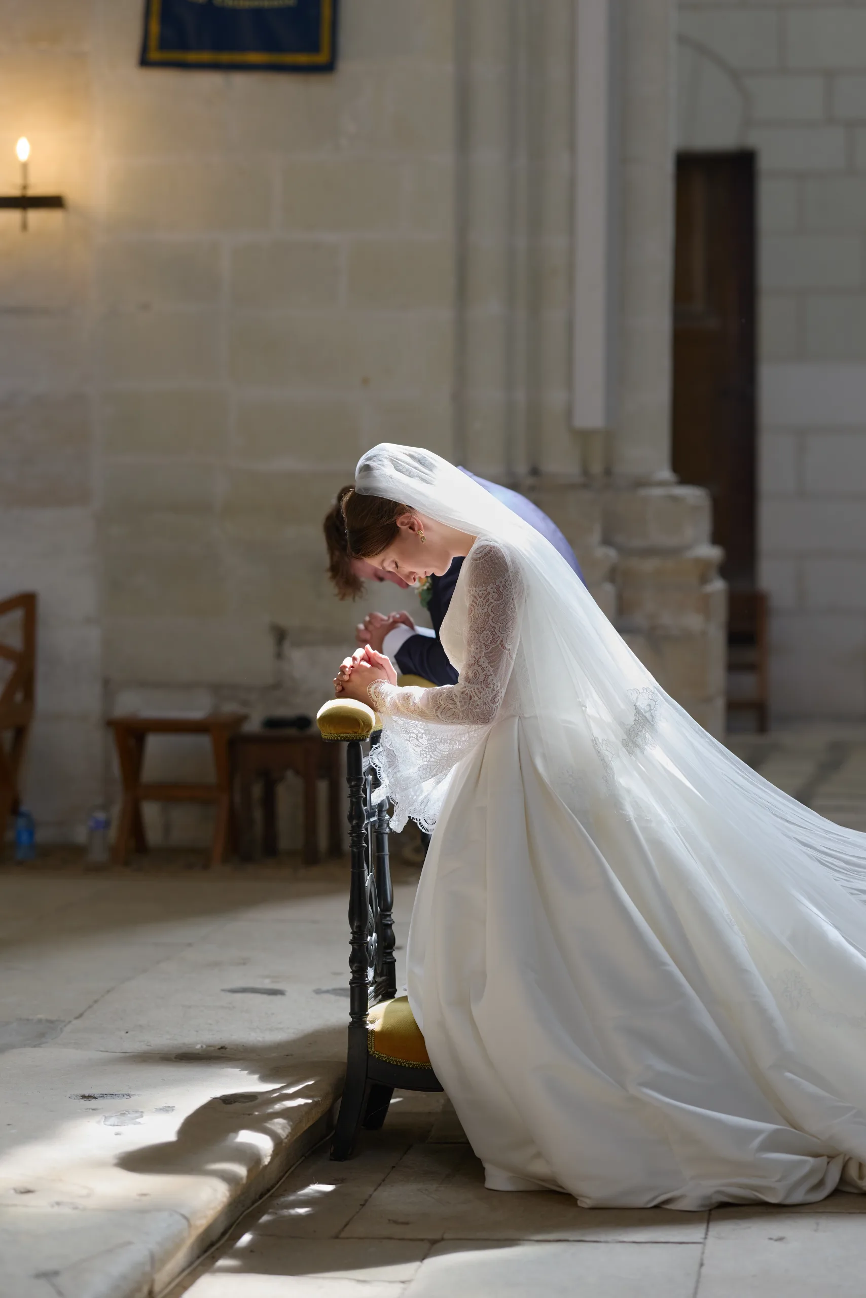 Femme en robe blanche agenouillée près d’un prie-Dieu