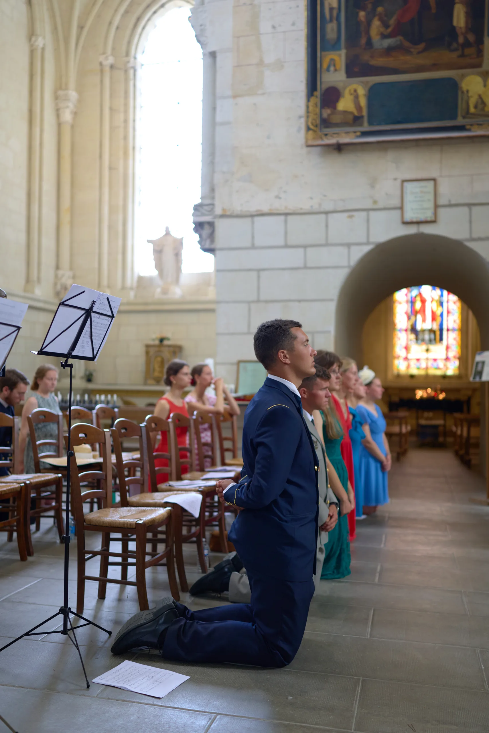 Un homme en costume bleu s’agenouille dans l’église