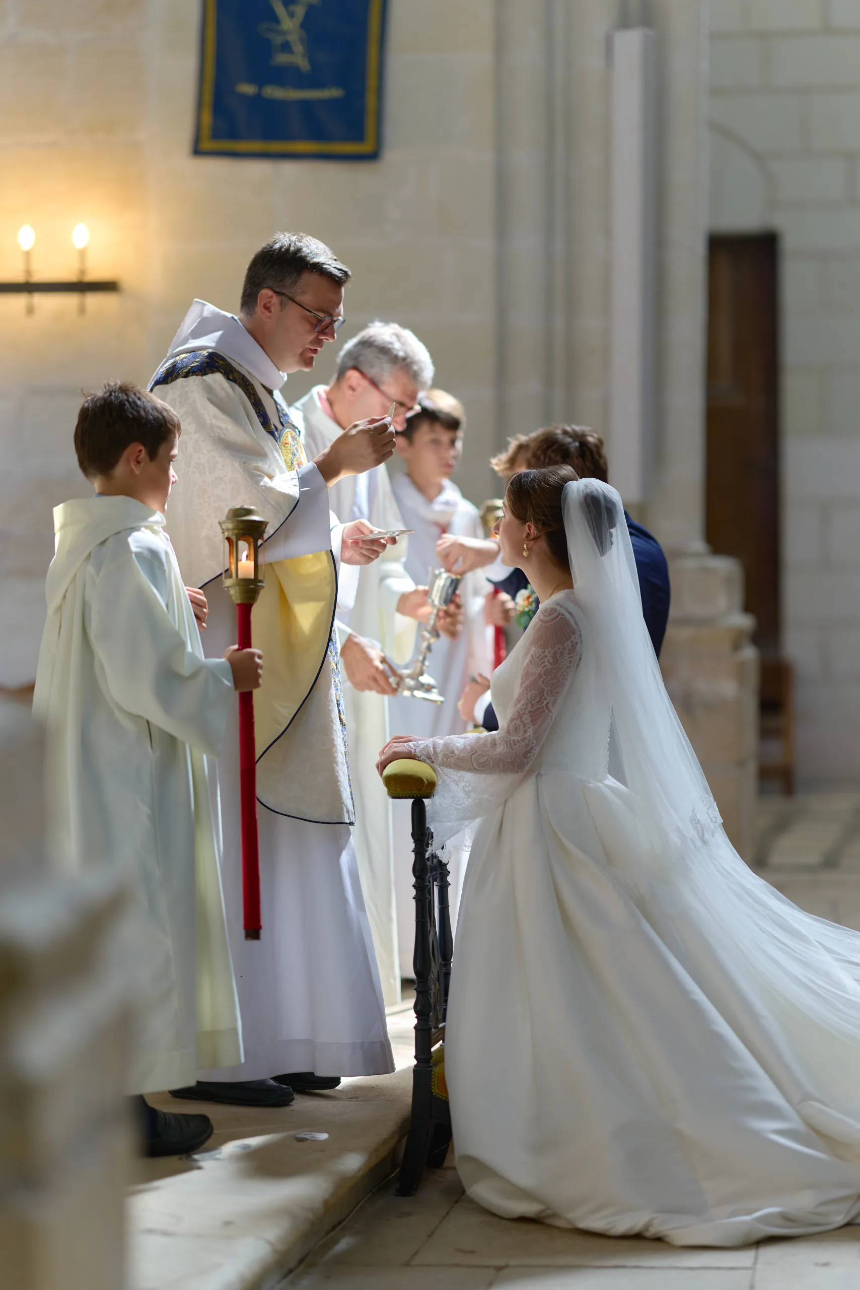 Prêtre et femme en robe blanche devant l’autel