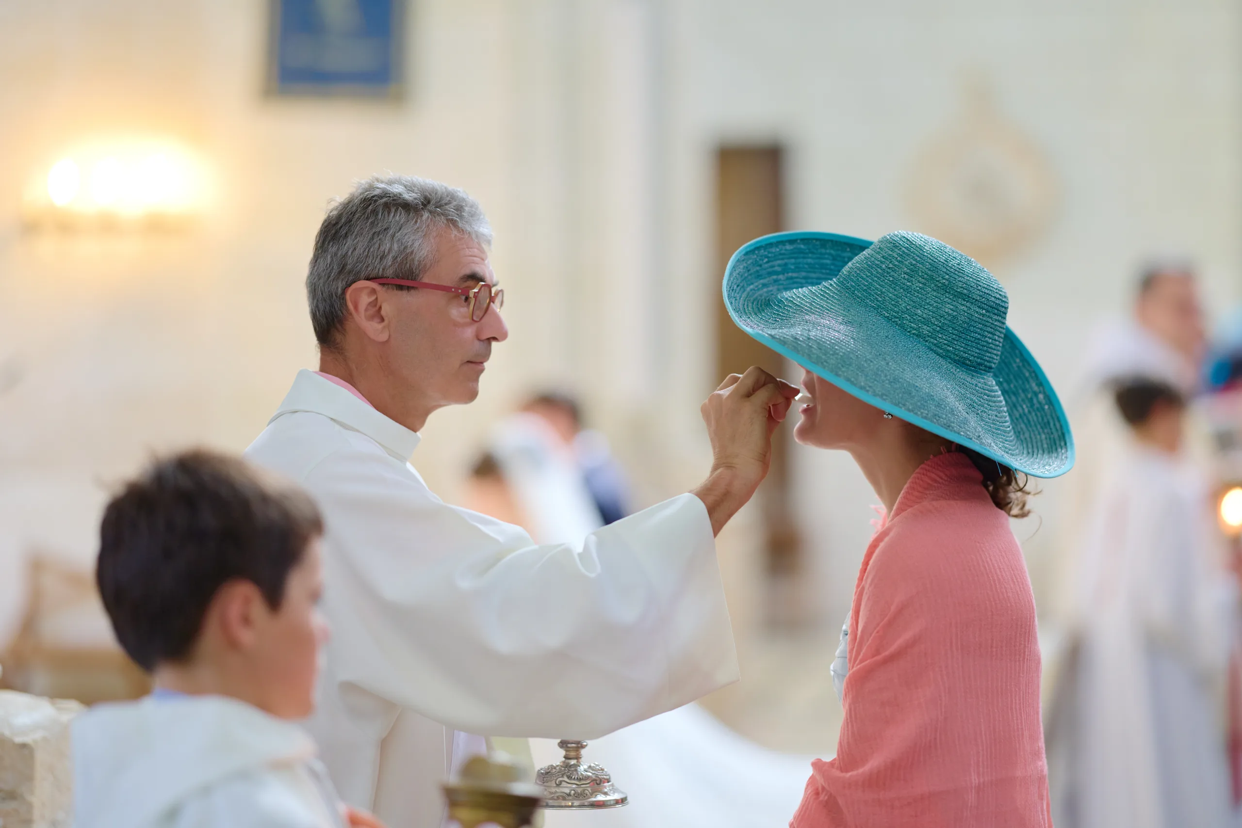 Prêtre ajustant le chapeau d’une invitée