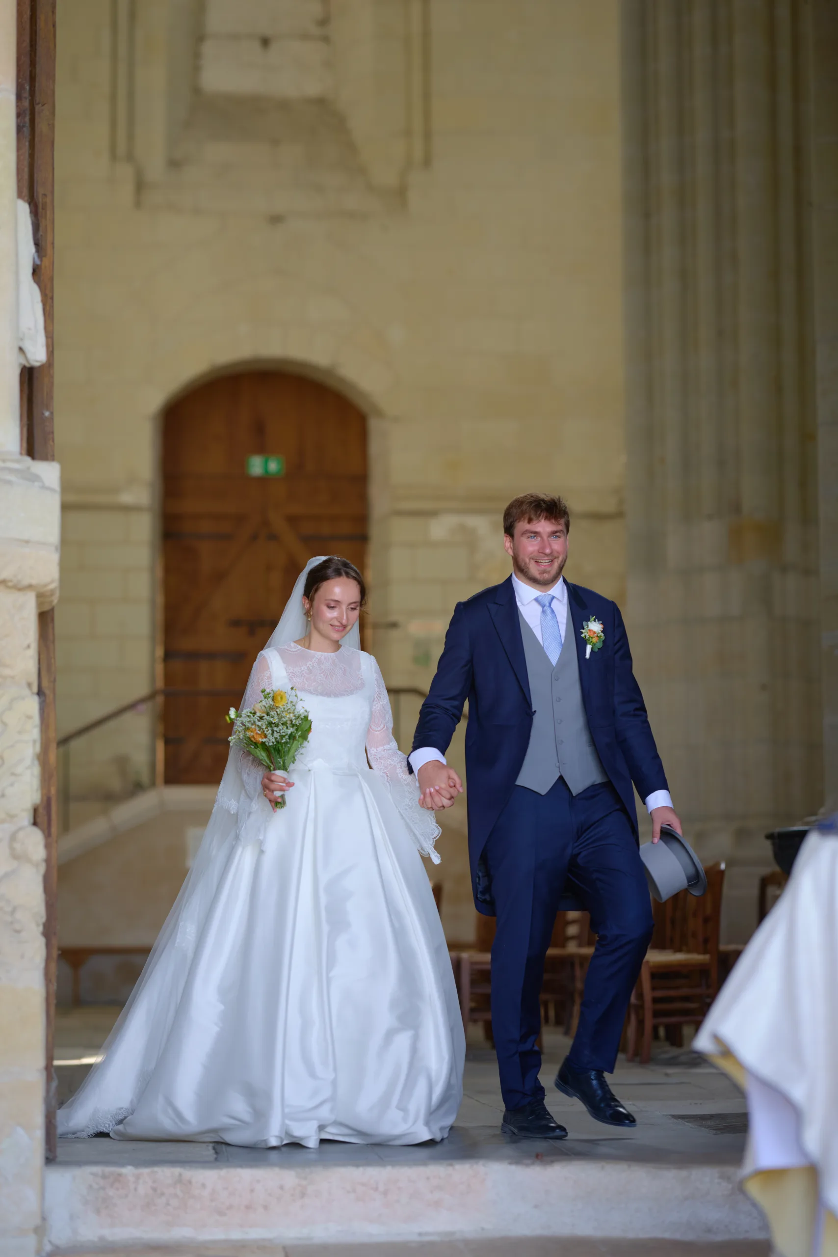 Les mariés se tiennent la main à la sortie de l’église