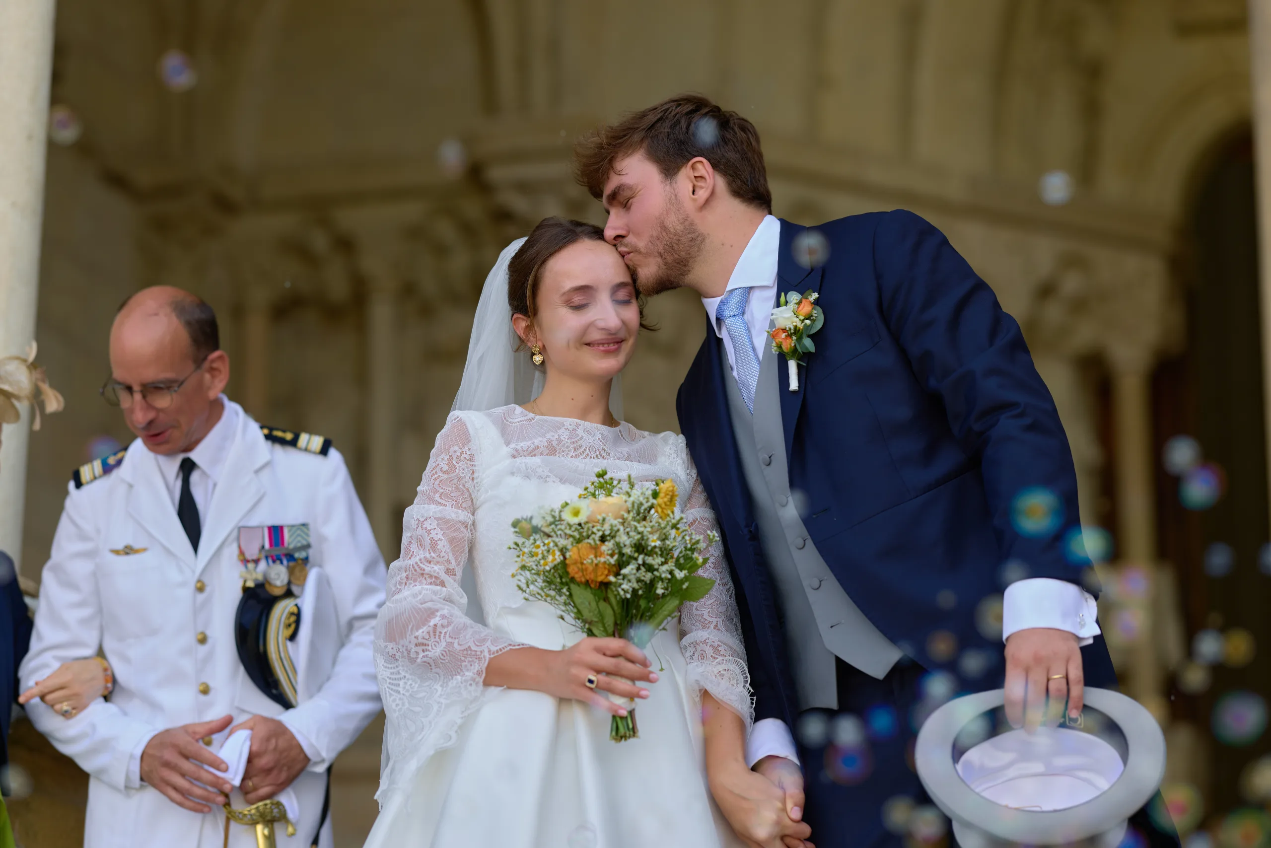 Le marié embrasse la mariée sur le front parmi les invités