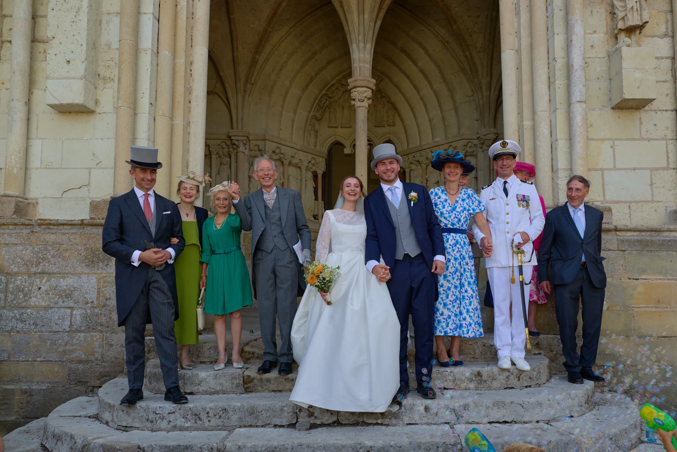 Les mariés posent avec leurs invités devant l’église