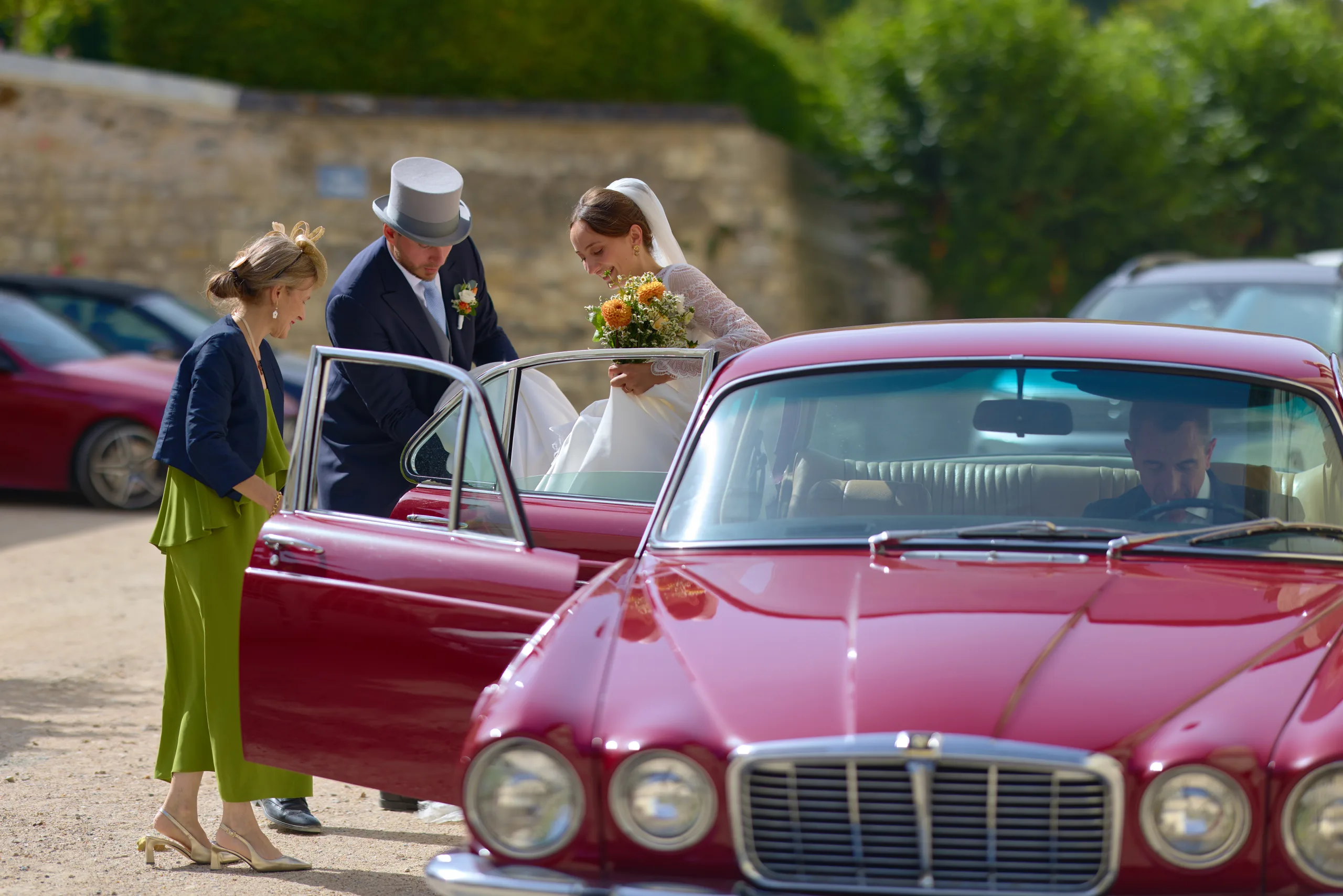 La mariée près d’une voiture rouge dont la portière est ouverte