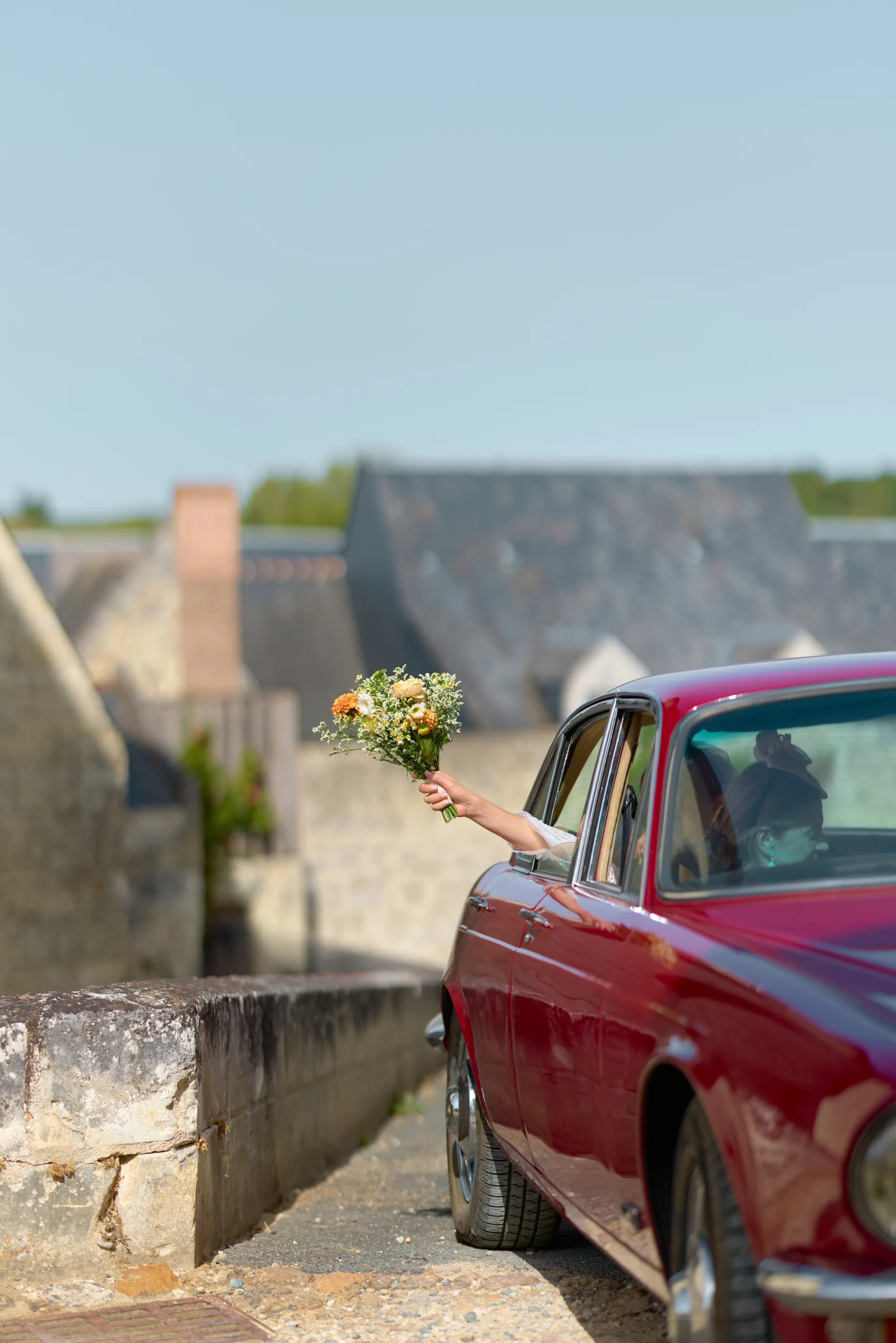 Une voiture rouge sur une place bordée de maisons