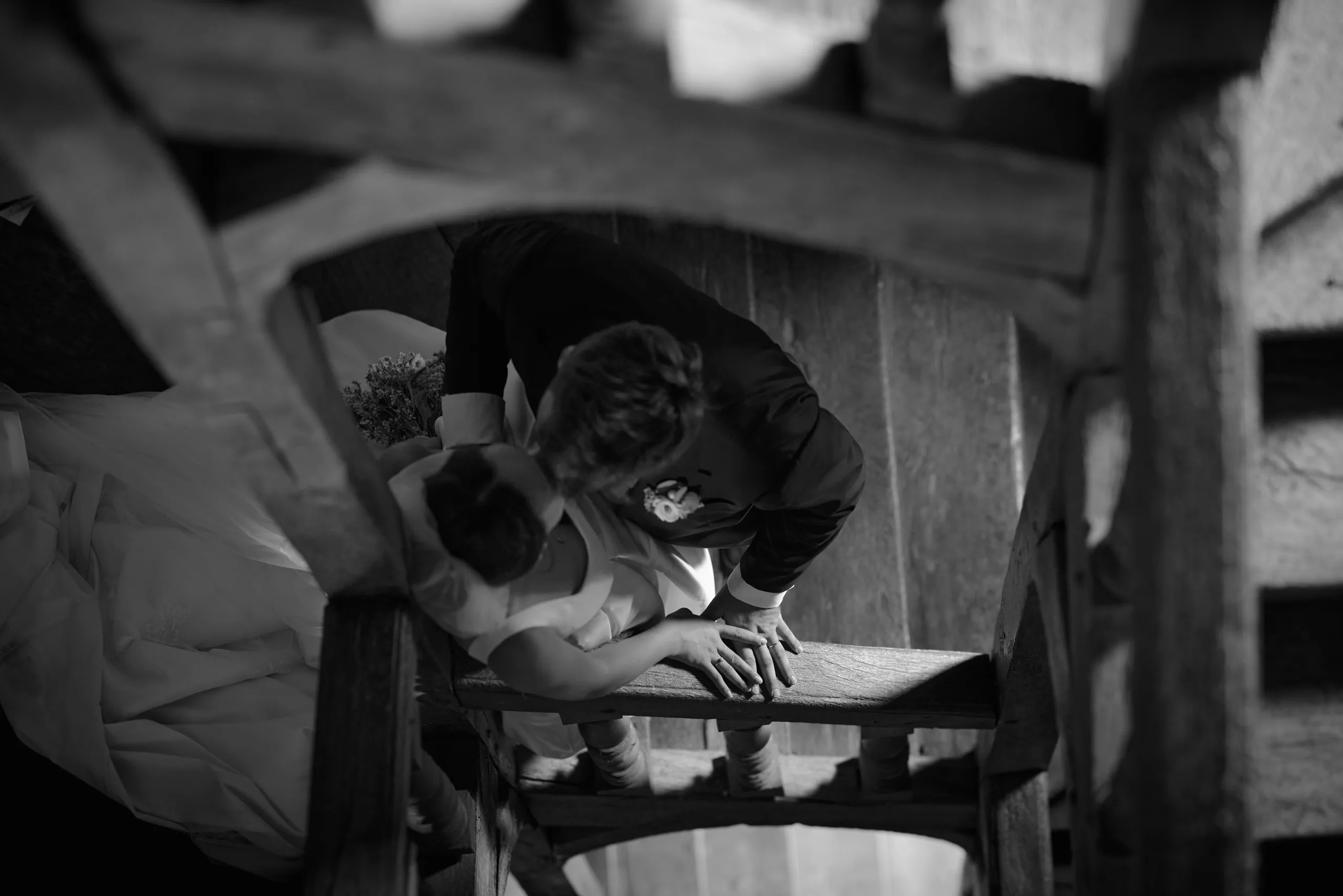 Les mariés s’embrassent dans un escalier, en noir et blanc