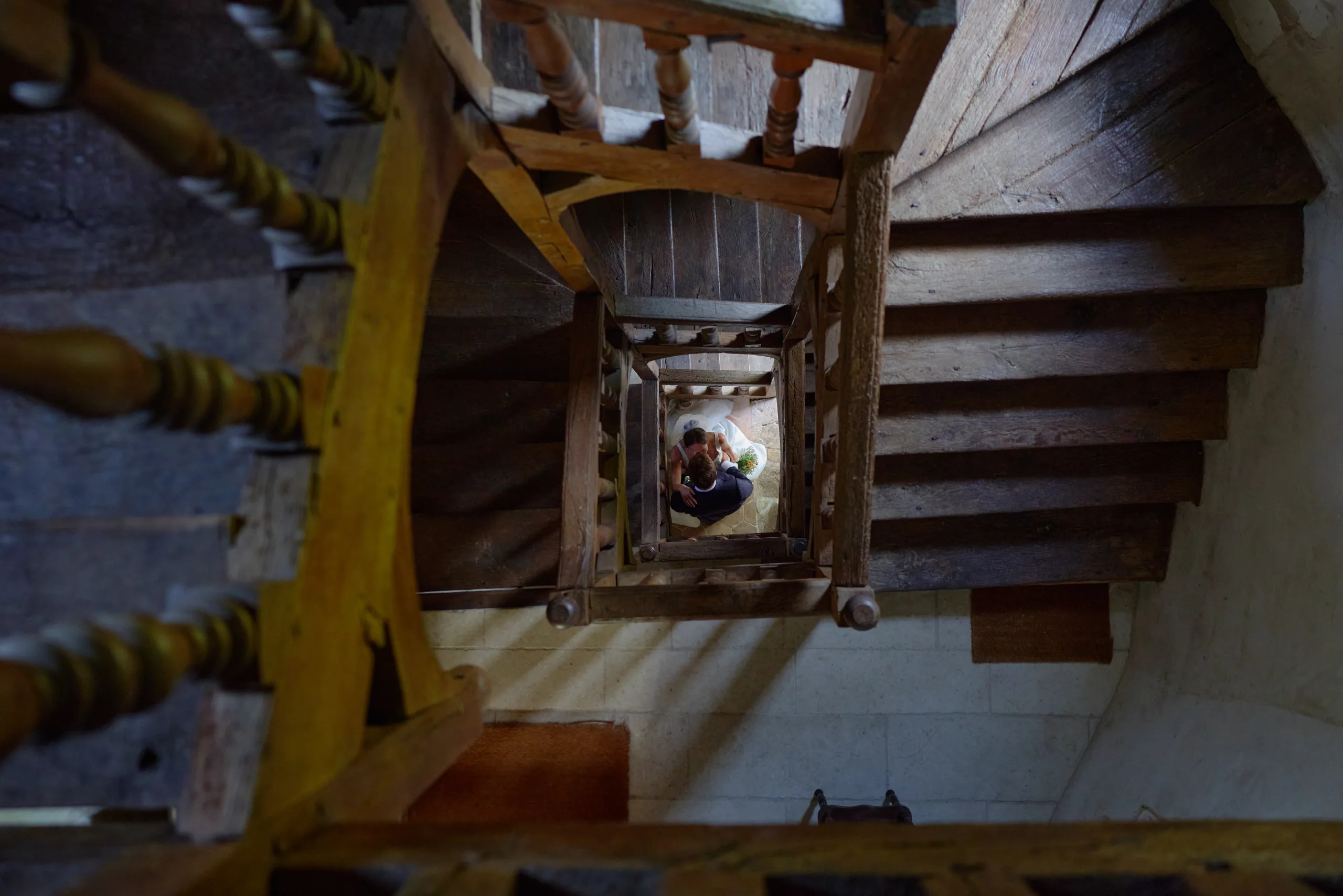 Vue plongeante d’un escalier en bois avec les mariés en contrebas