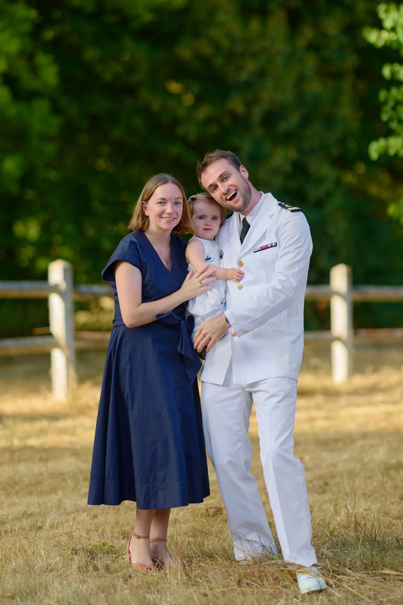 Un homme et une femme posent avec un bébé dans le jardin