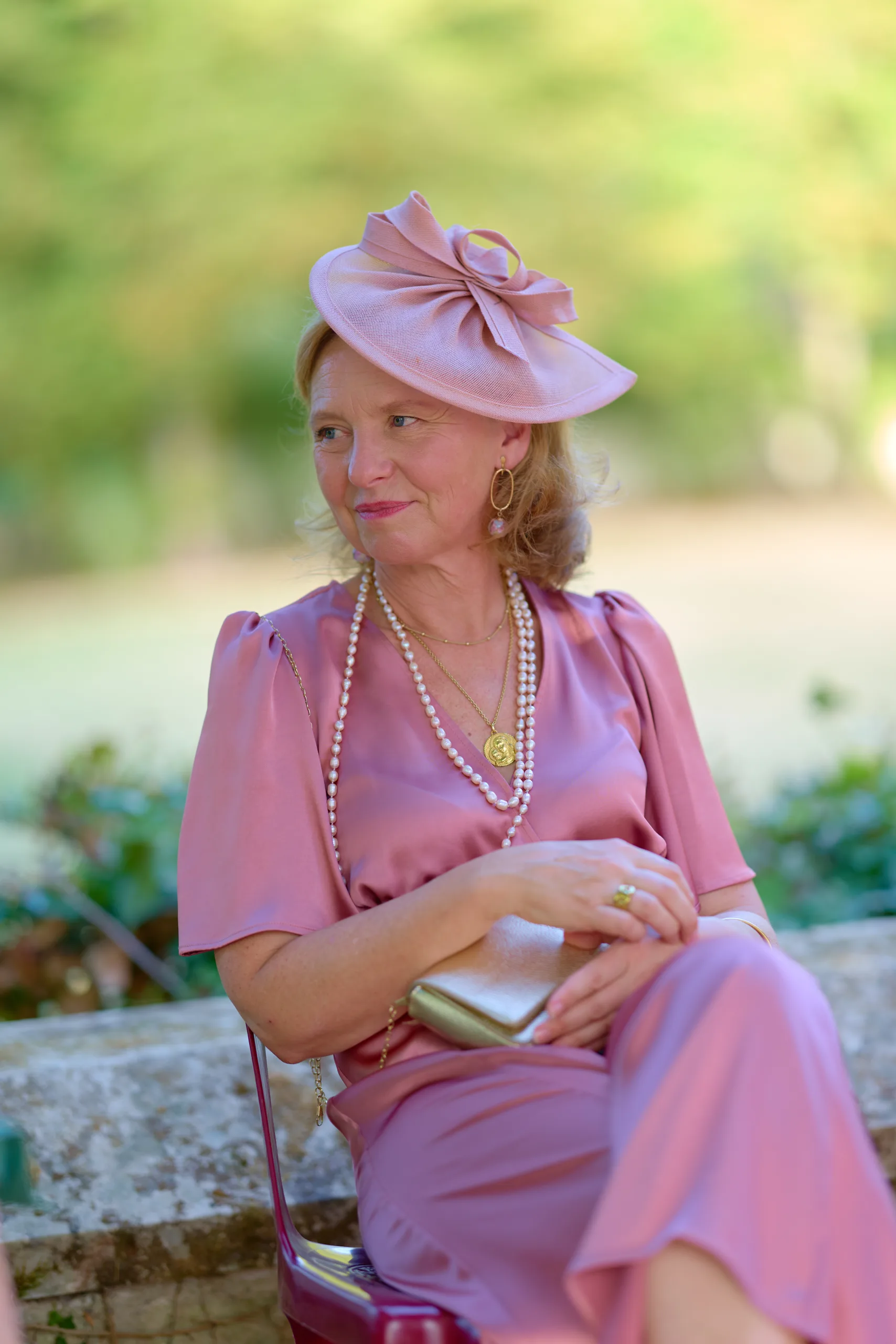 Une invitée assise en robe et chapeau roses