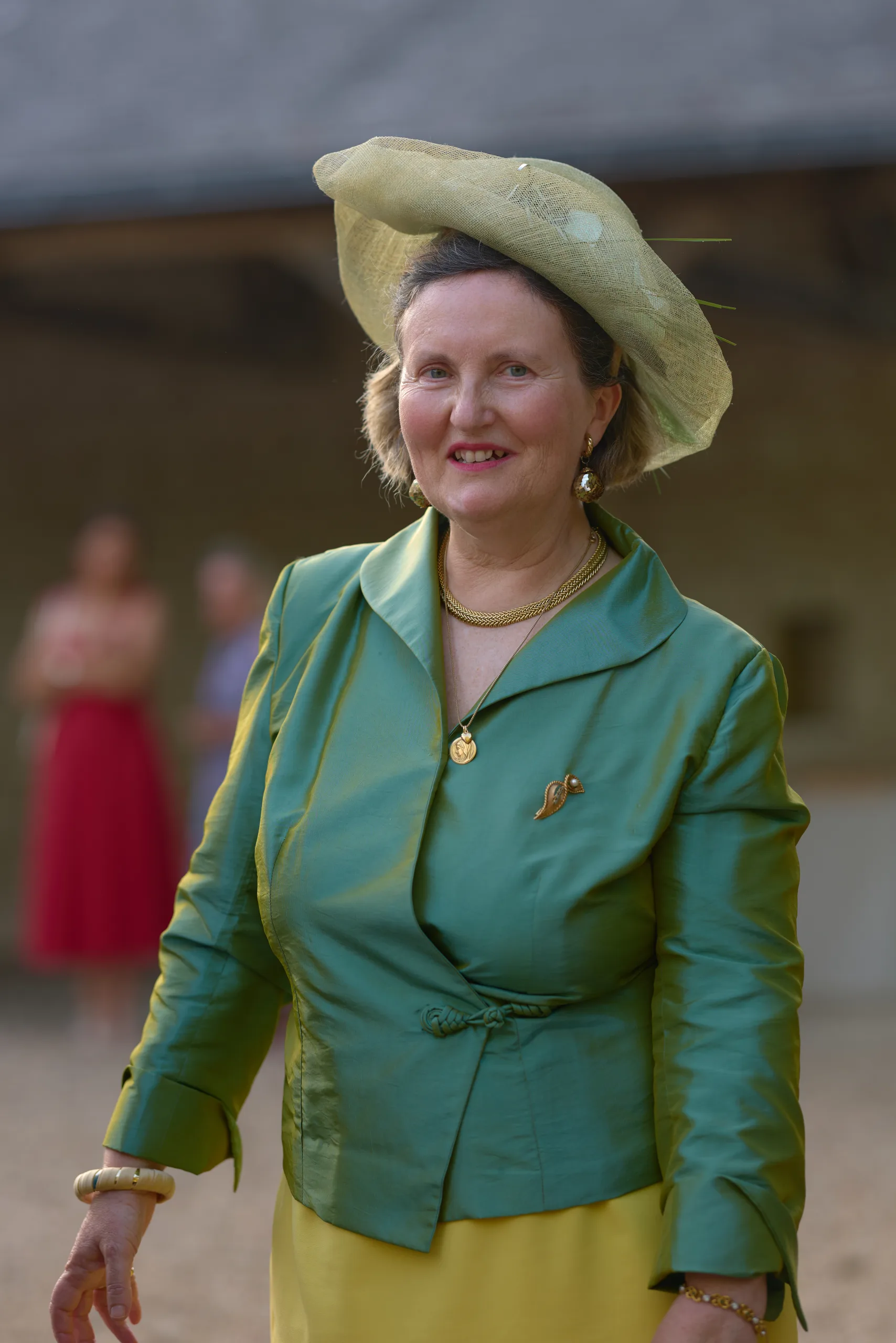 Une invitée en veste verte et chapeau jaune