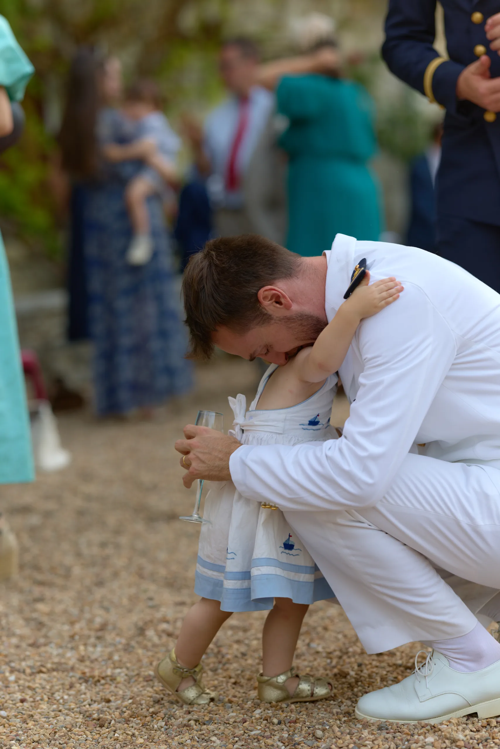 Un homme en uniforme blanc se penche vers une petite fille