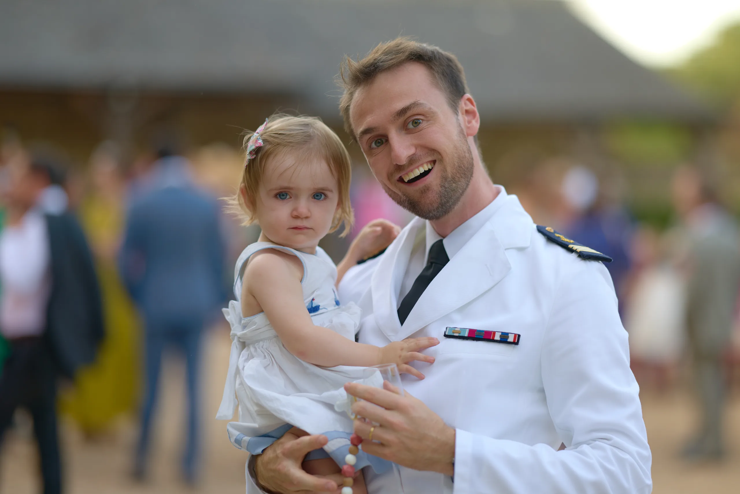 Un invité en uniforme blanc porte un enfant