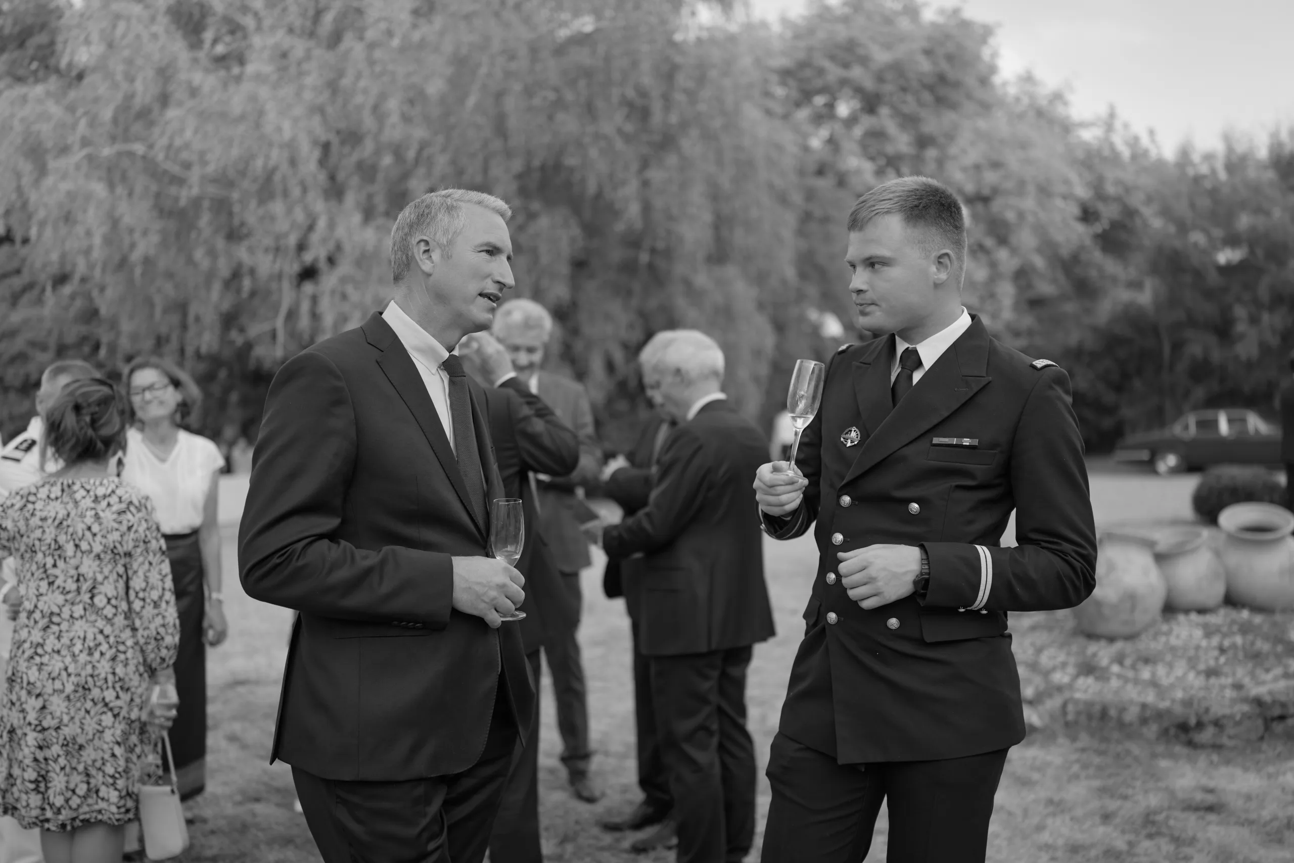 Deux invités en costume discutent, en noir et blanc