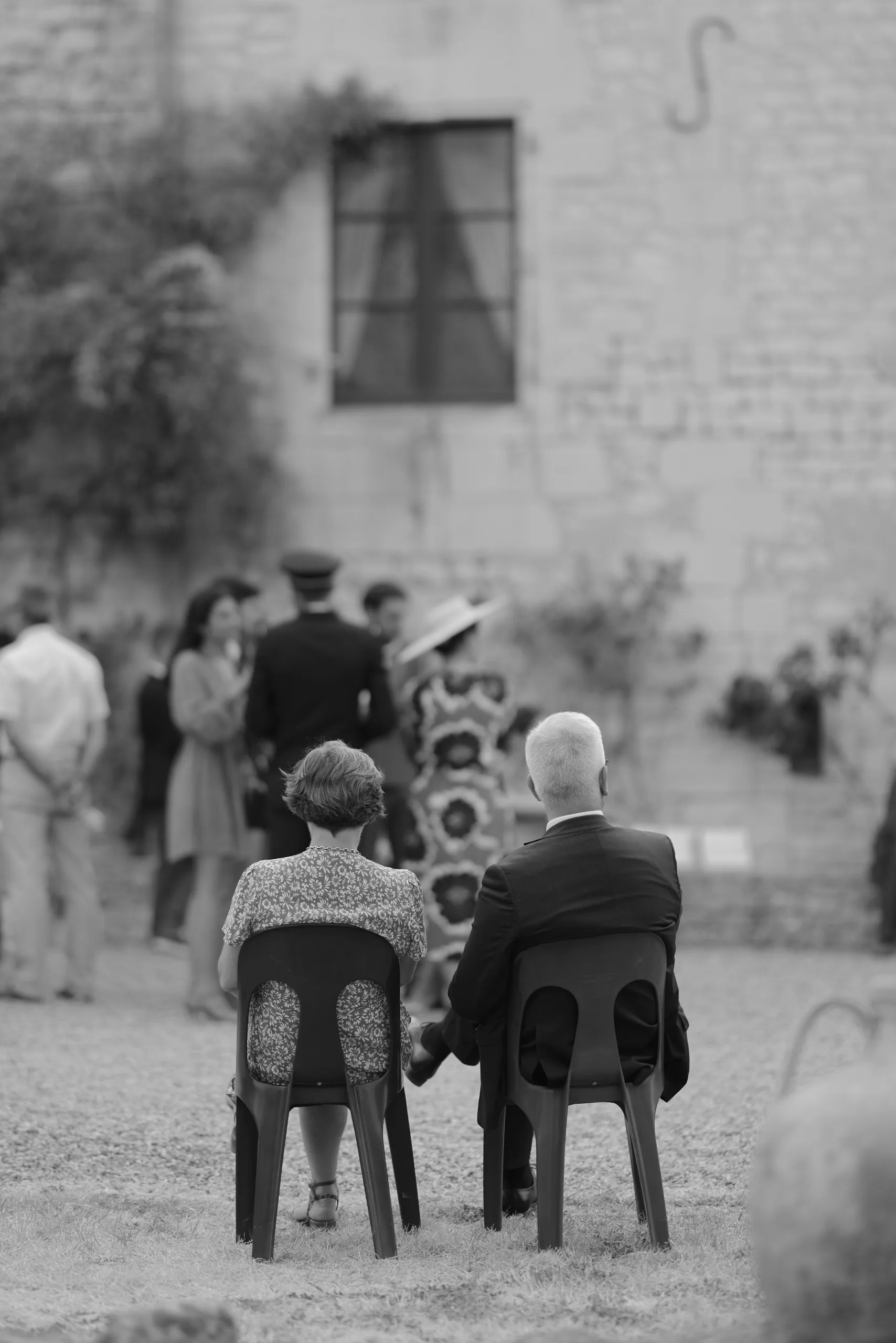 Des invités assis à une table dans la cour, en noir et blanc
