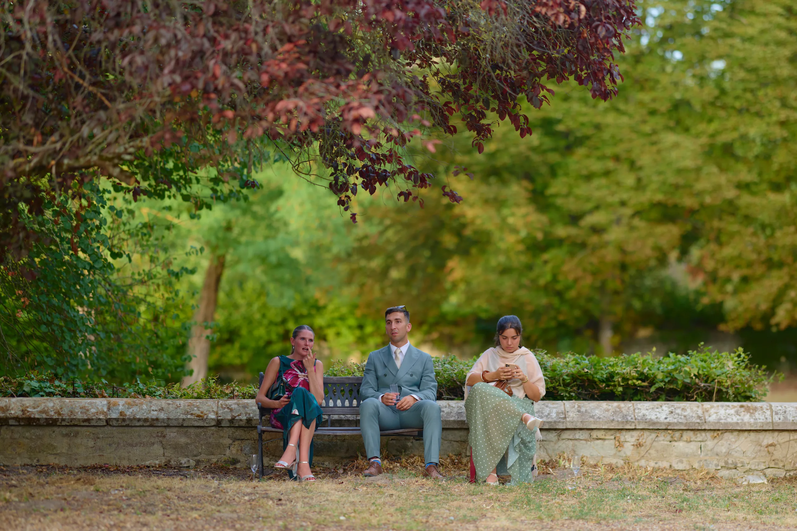 Trois invités assis sur un banc dans le jardin