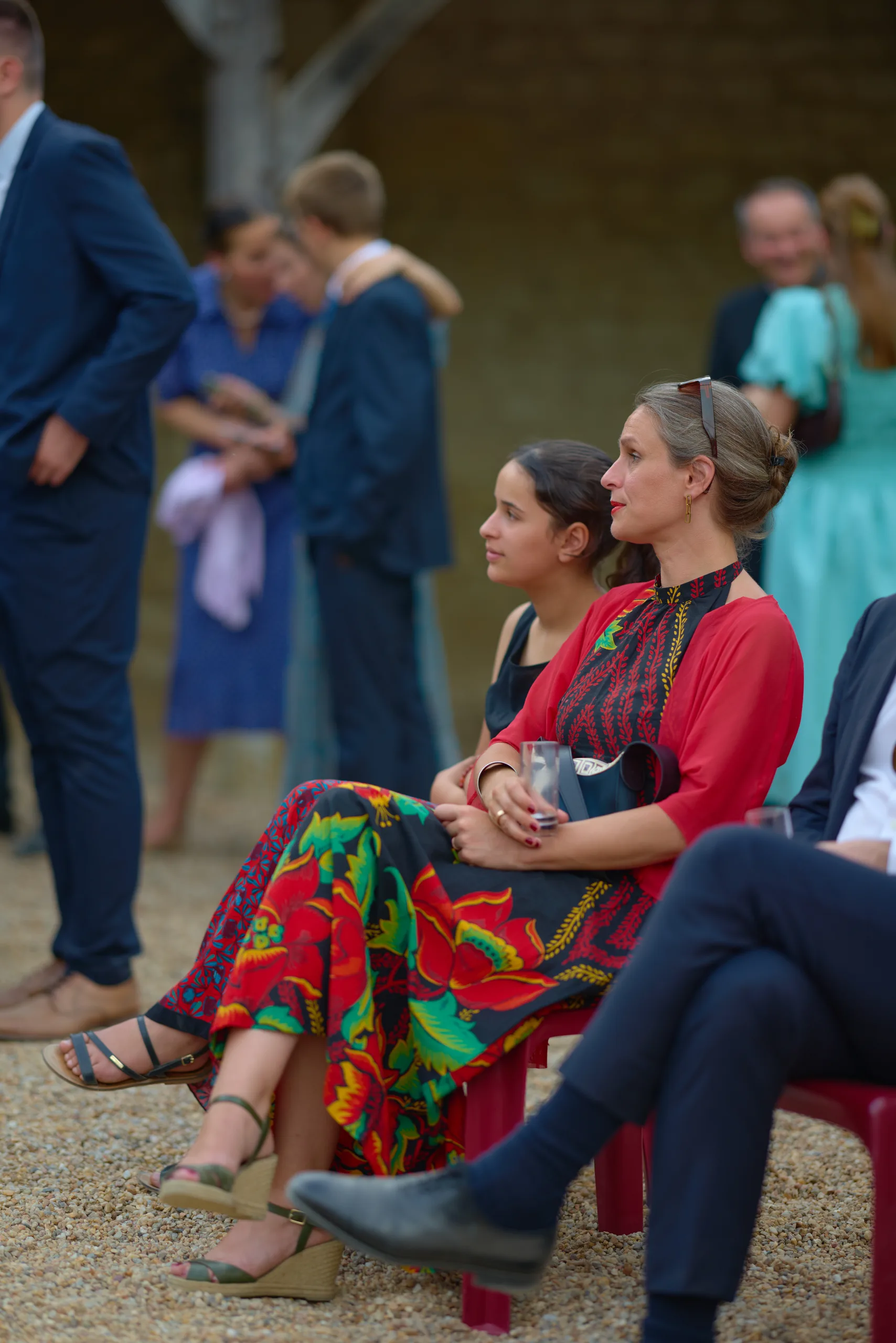 Une invitée en robe à fleurs assise dans la cour