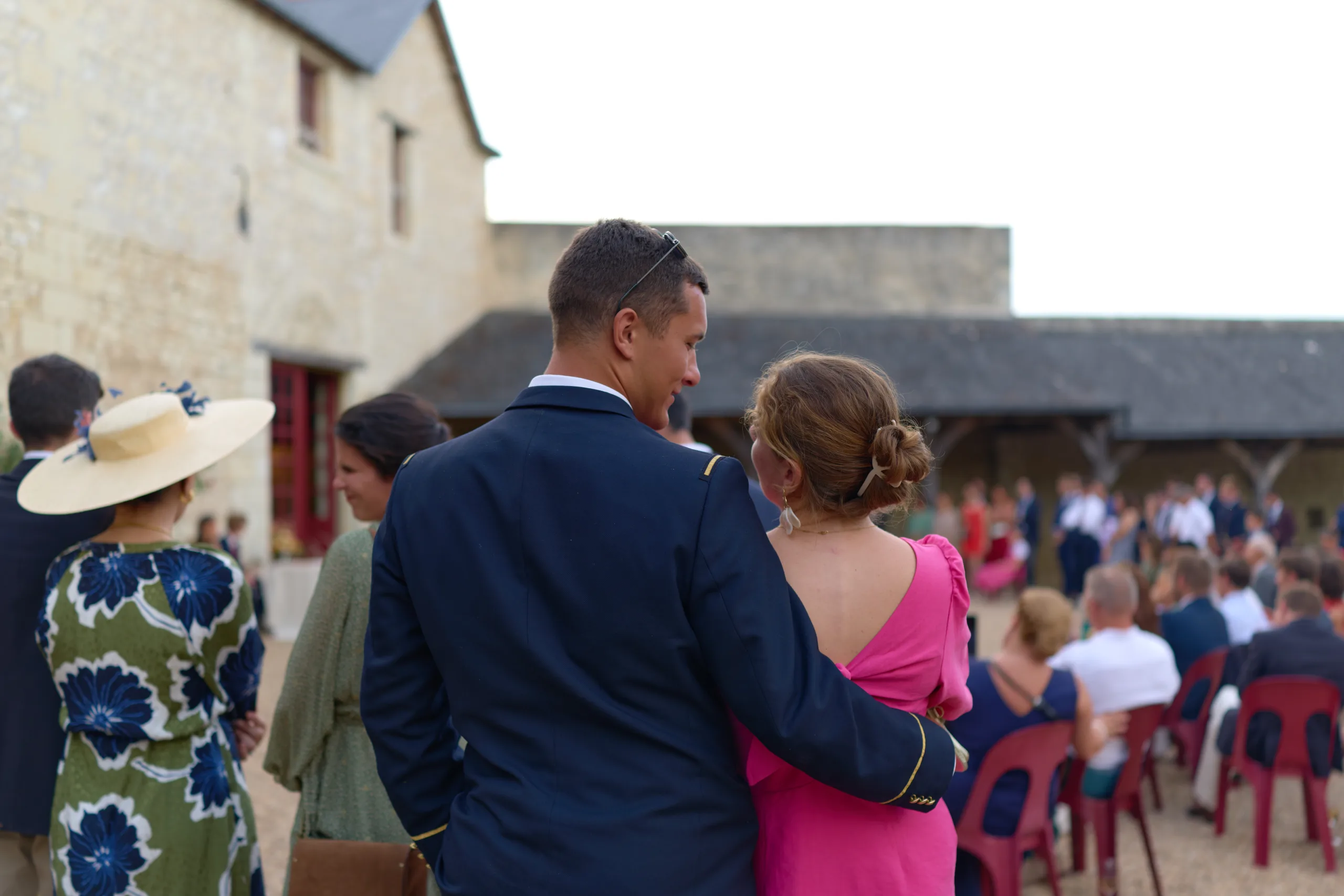 Un homme enlace une invitée en rose dans la cour