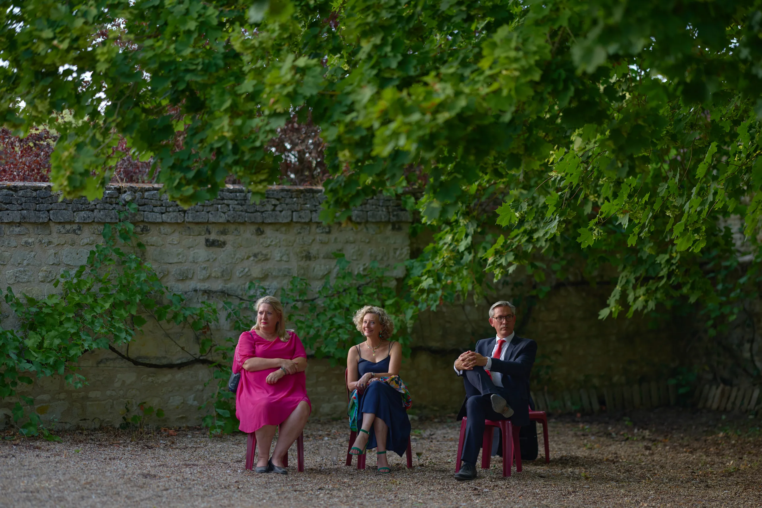 Trois invités assis sur un banc sous les arbres