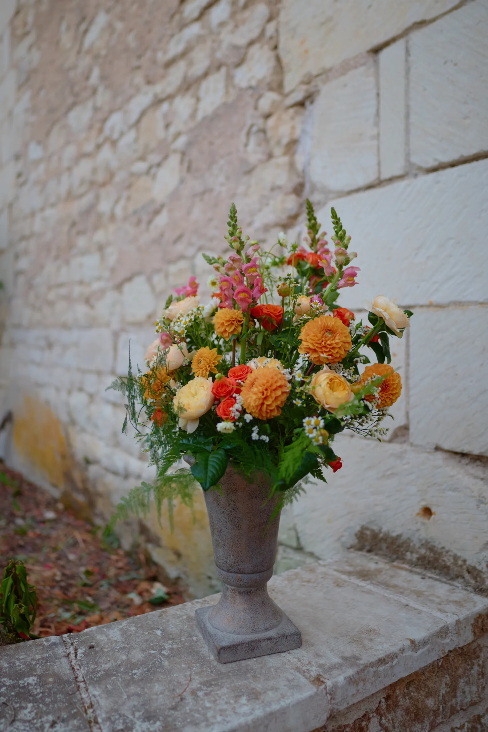 Un bouquet de fleurs jaunes et orange près d’un mur en pierre