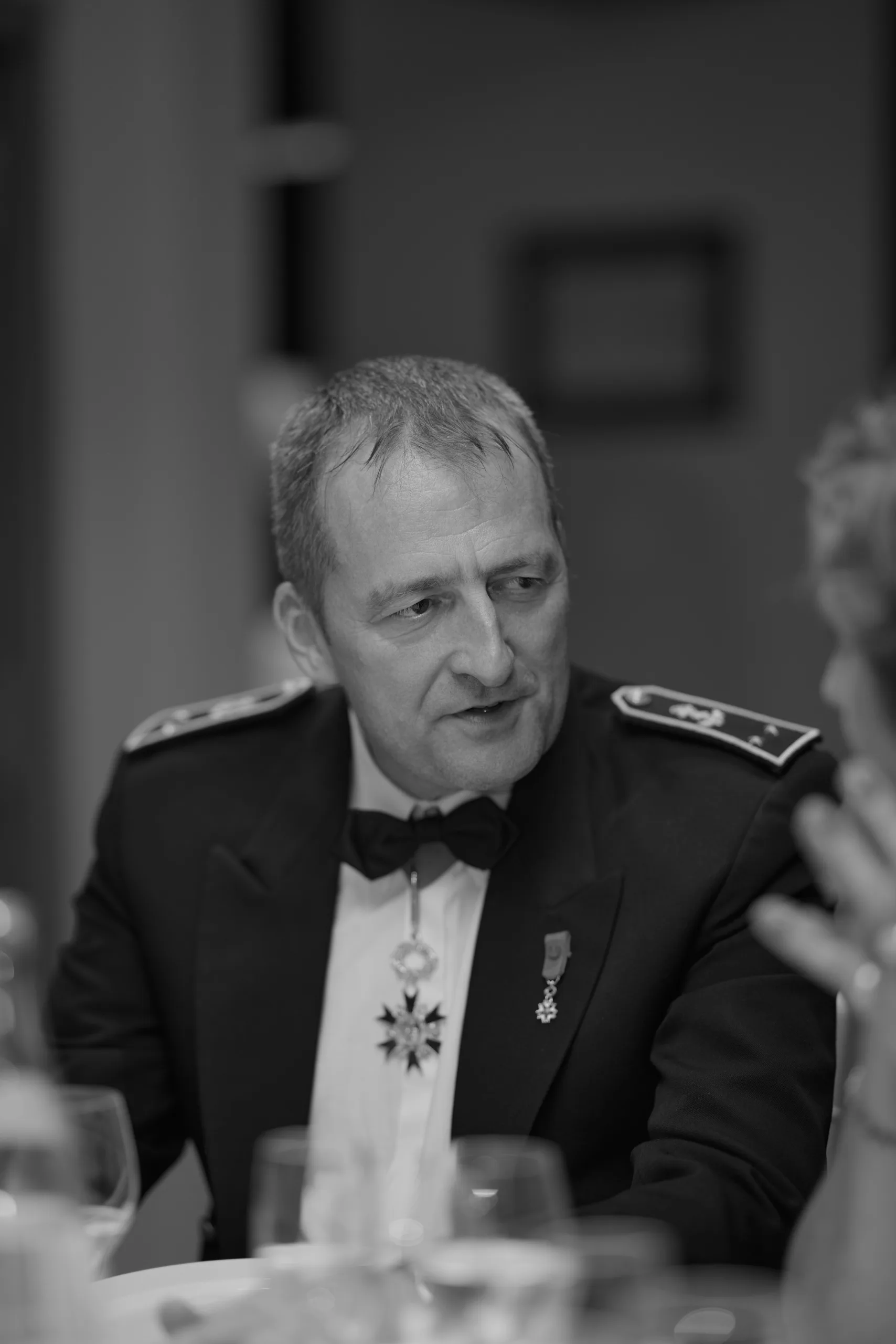 Un invité en uniforme militaire à table, en noir et blanc