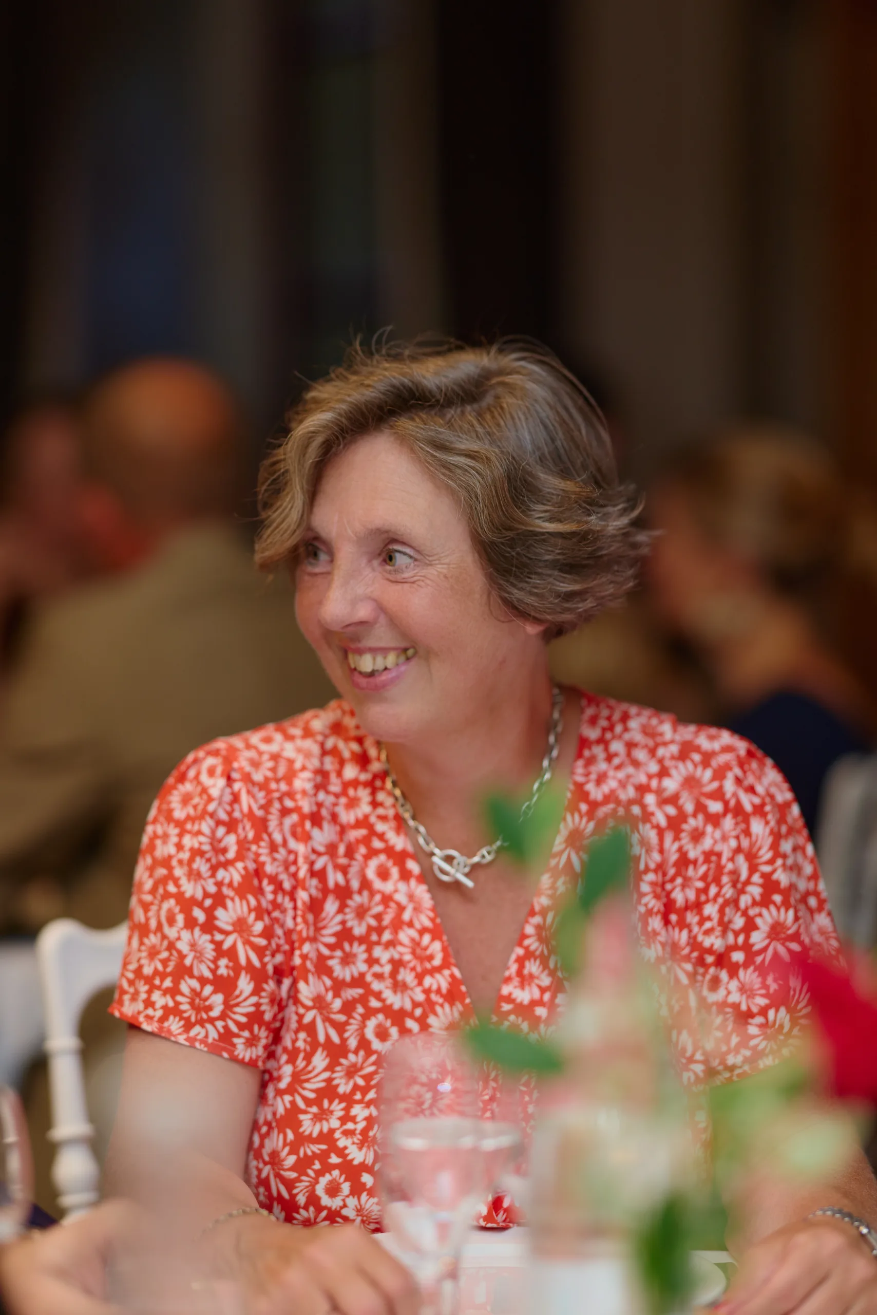 Une invitée en robe à motifs sourit à table