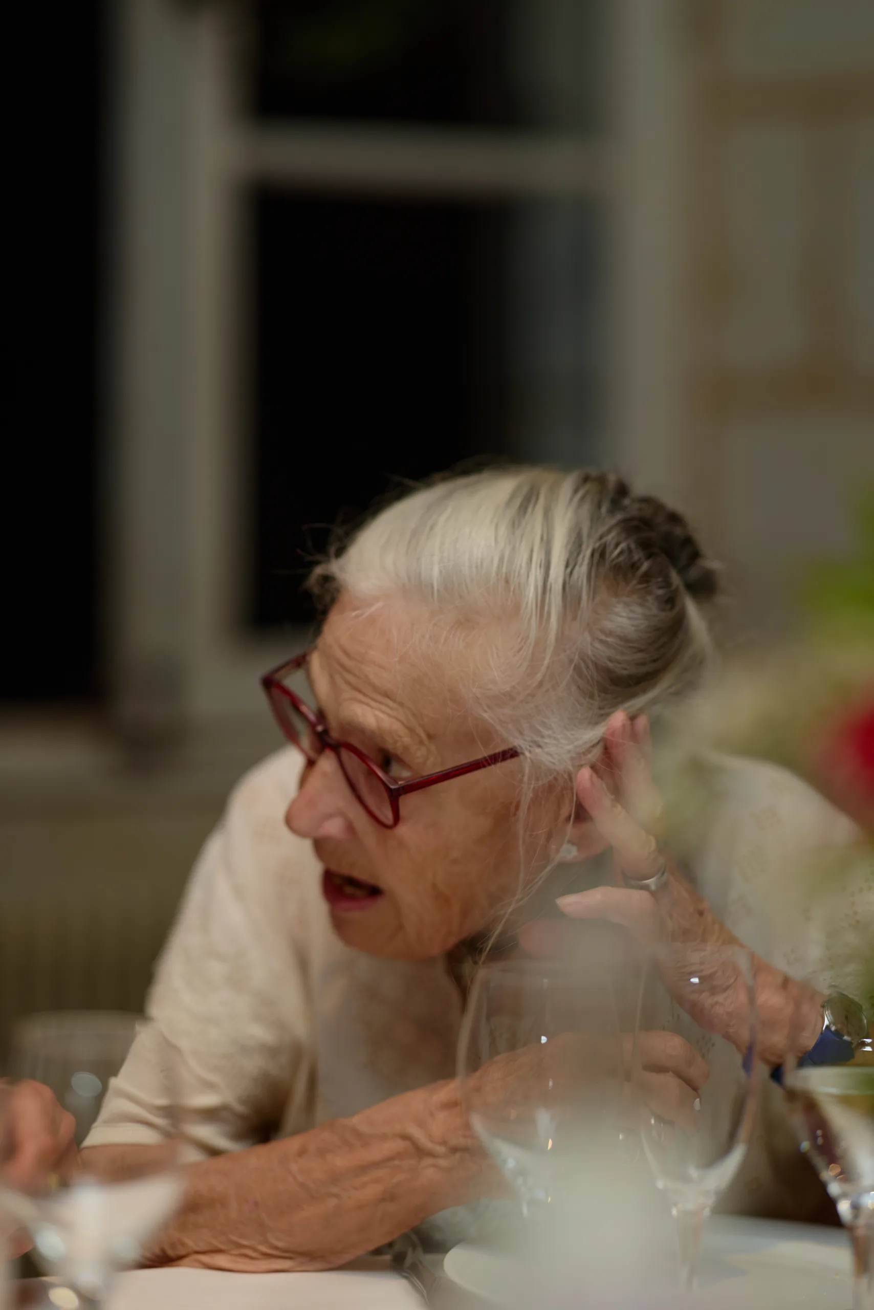 Une invitée aux cheveux blancs et aux lunettes rouges à table