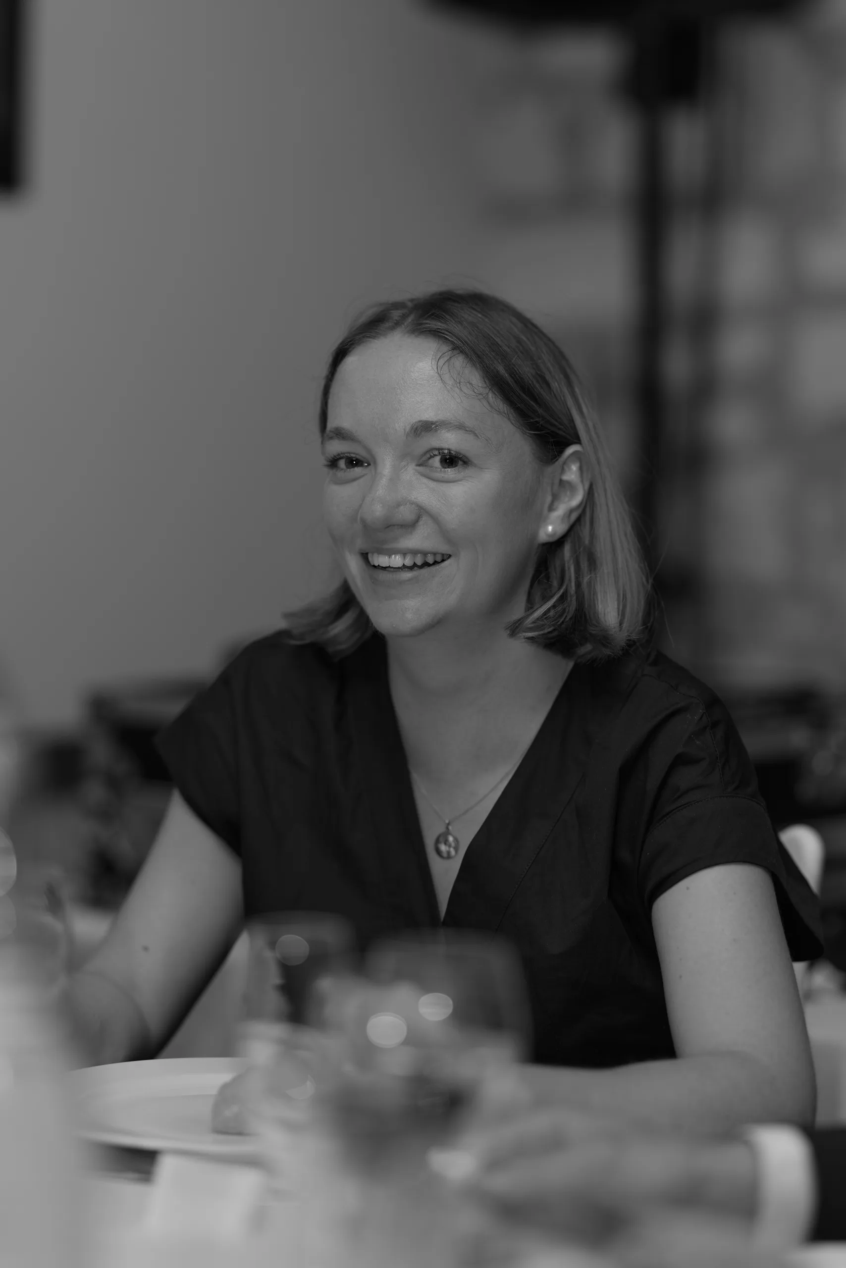 Une invitée sourit à table, en noir et blanc