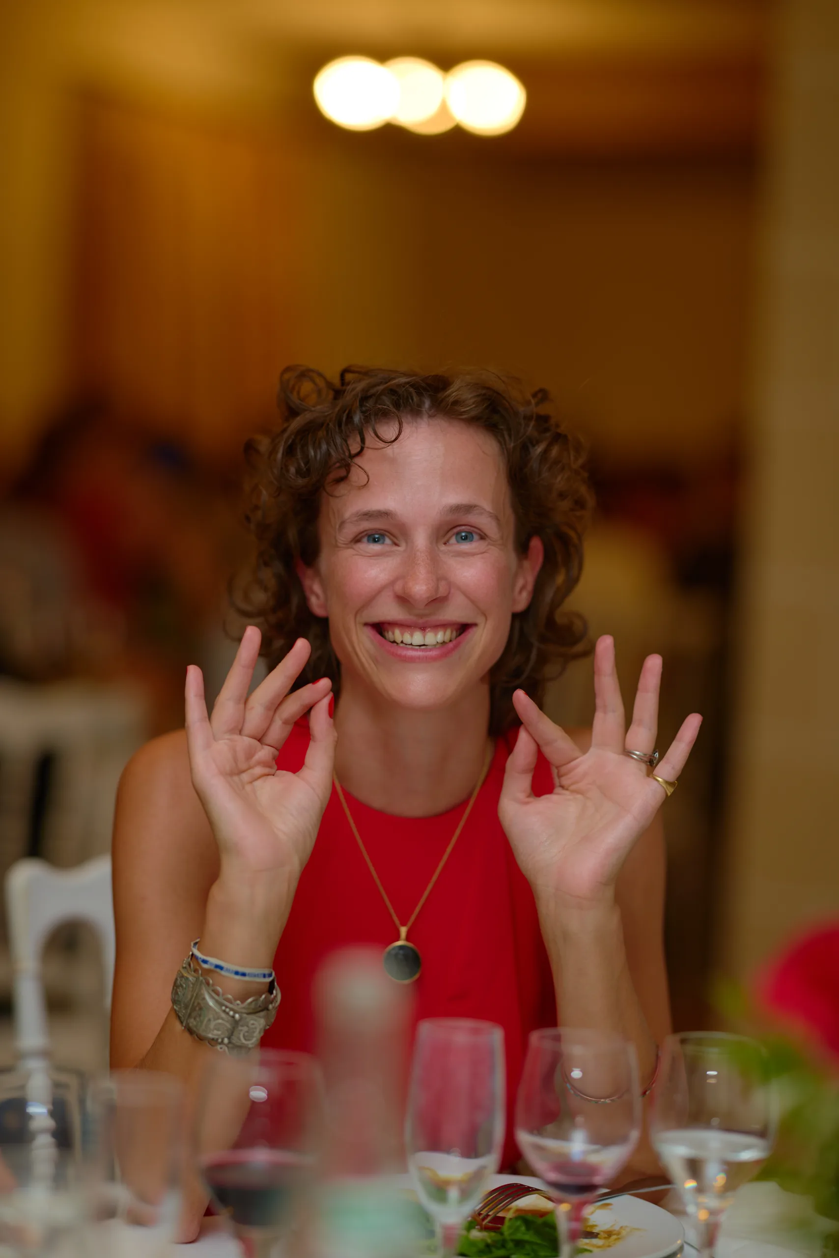Une invitée en robe rouge fait des gestes avec ses mains