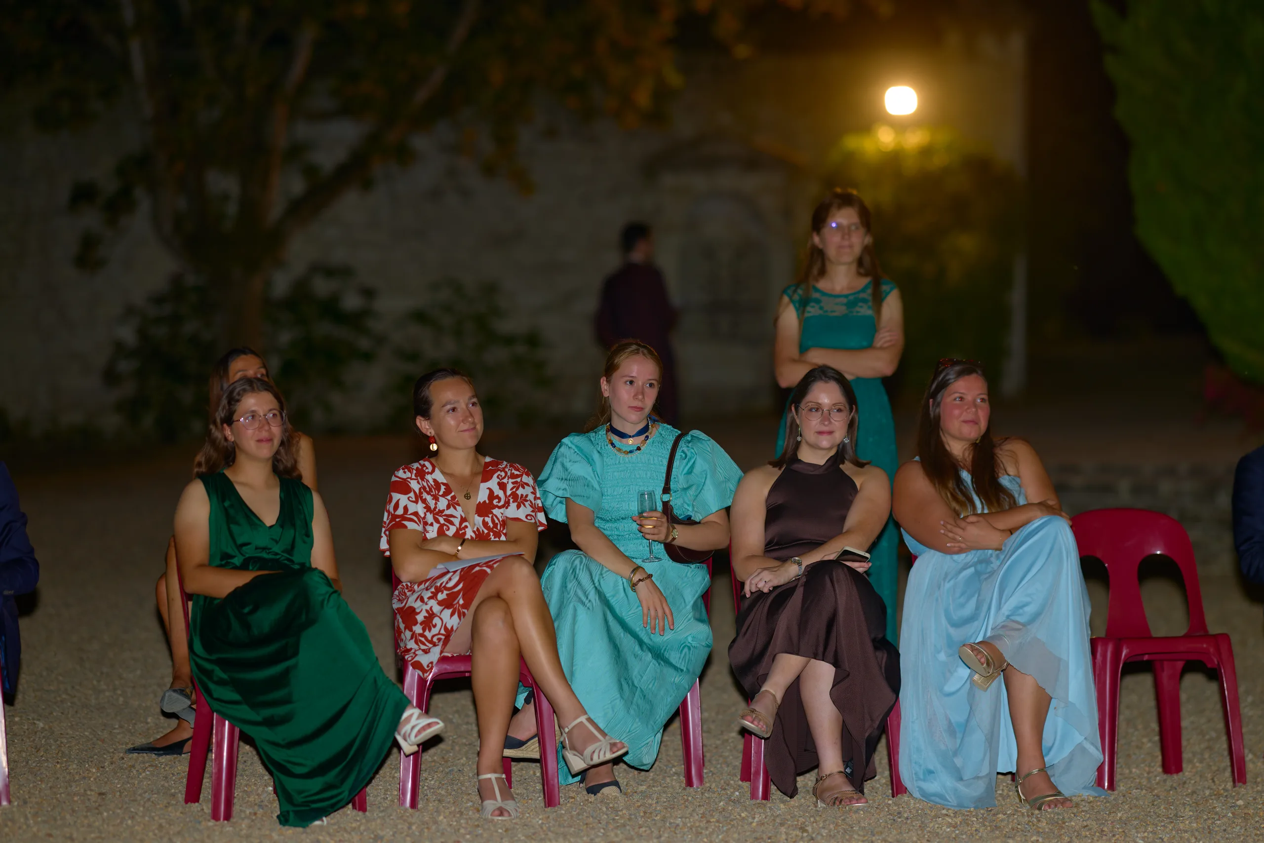 Des invitées assises sur des chaises rouges à la nuit tombée