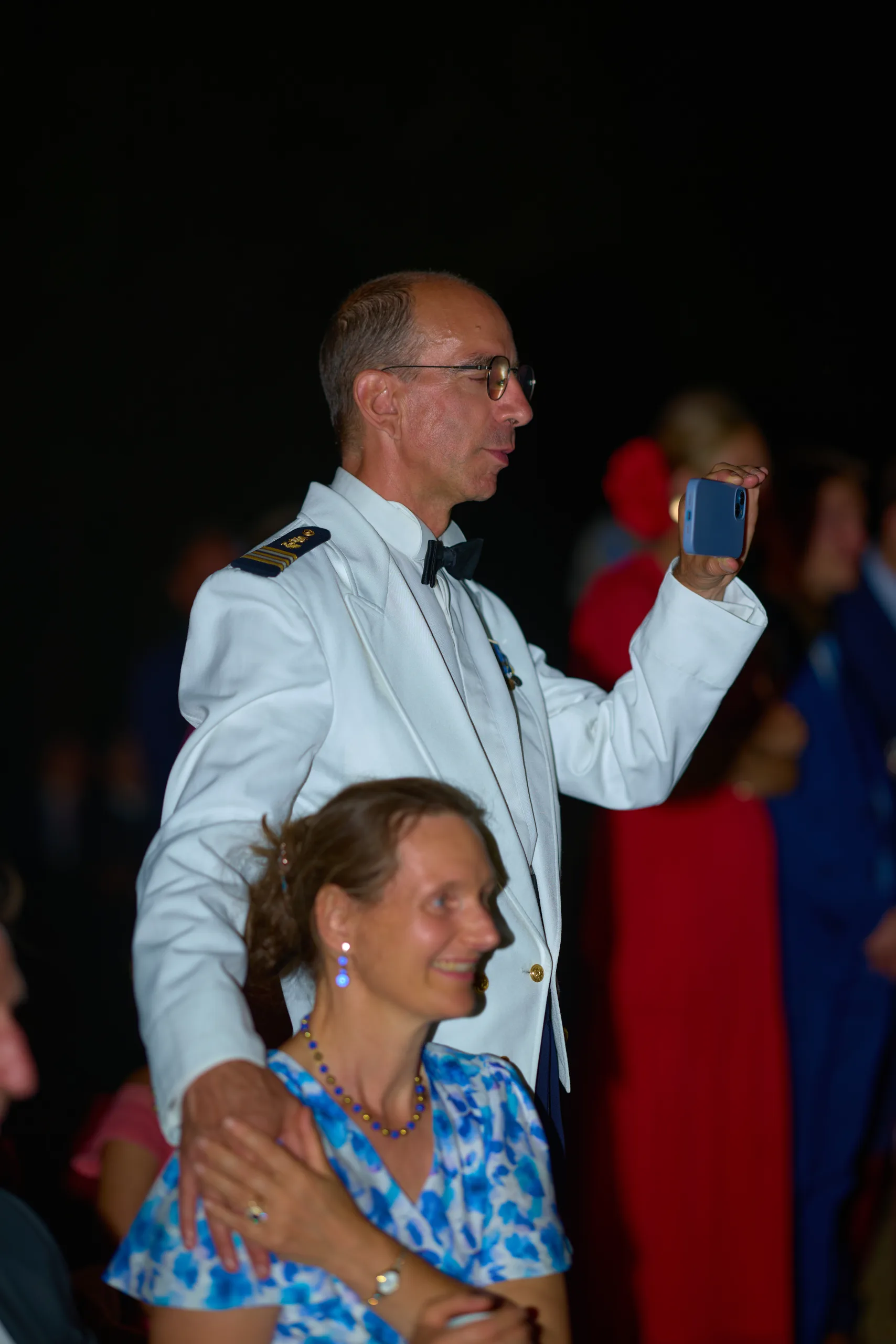 Un invité en uniforme blanc tient un téléphone pendant la soirée