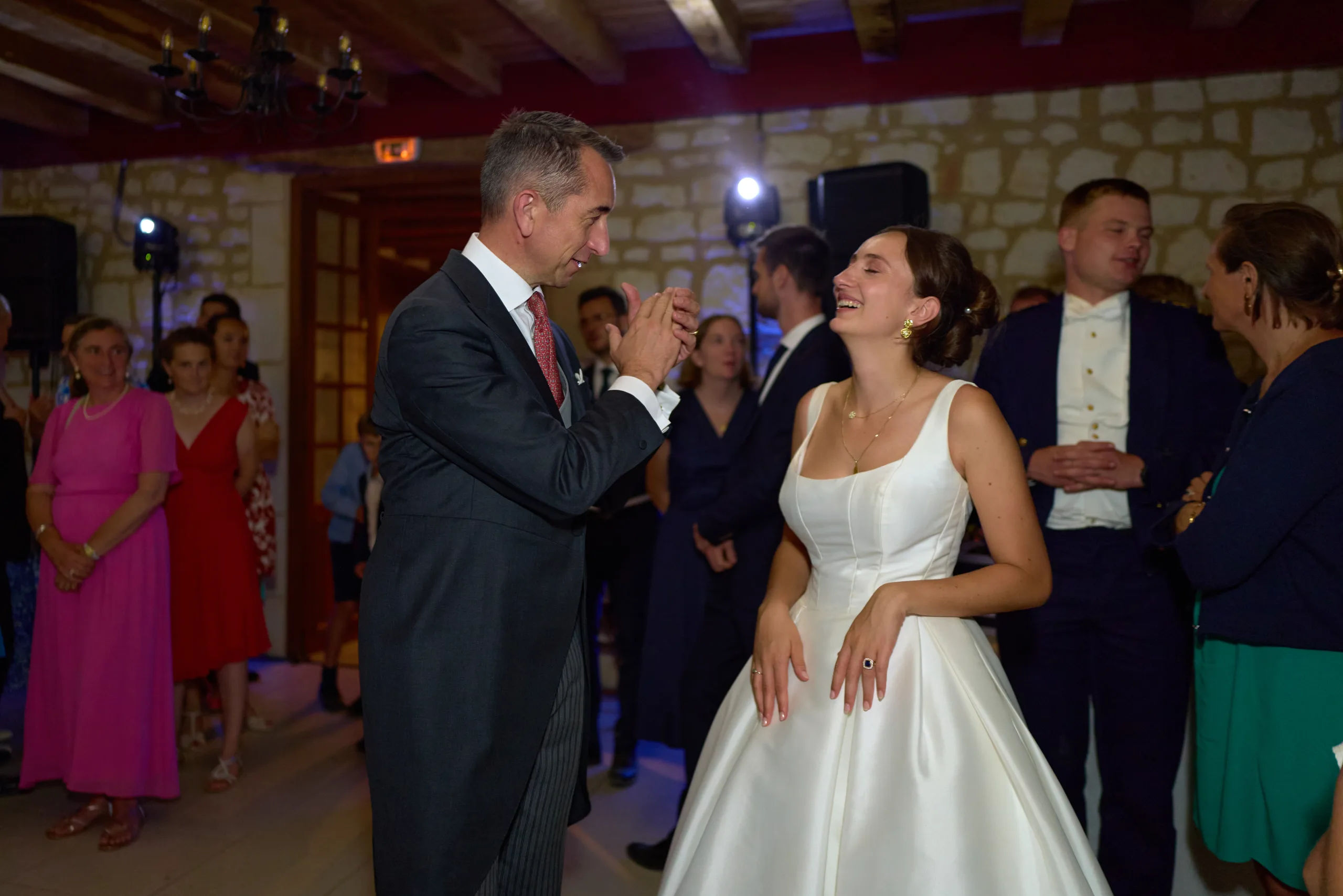 La mariée danse avec un invité devant les autres convives