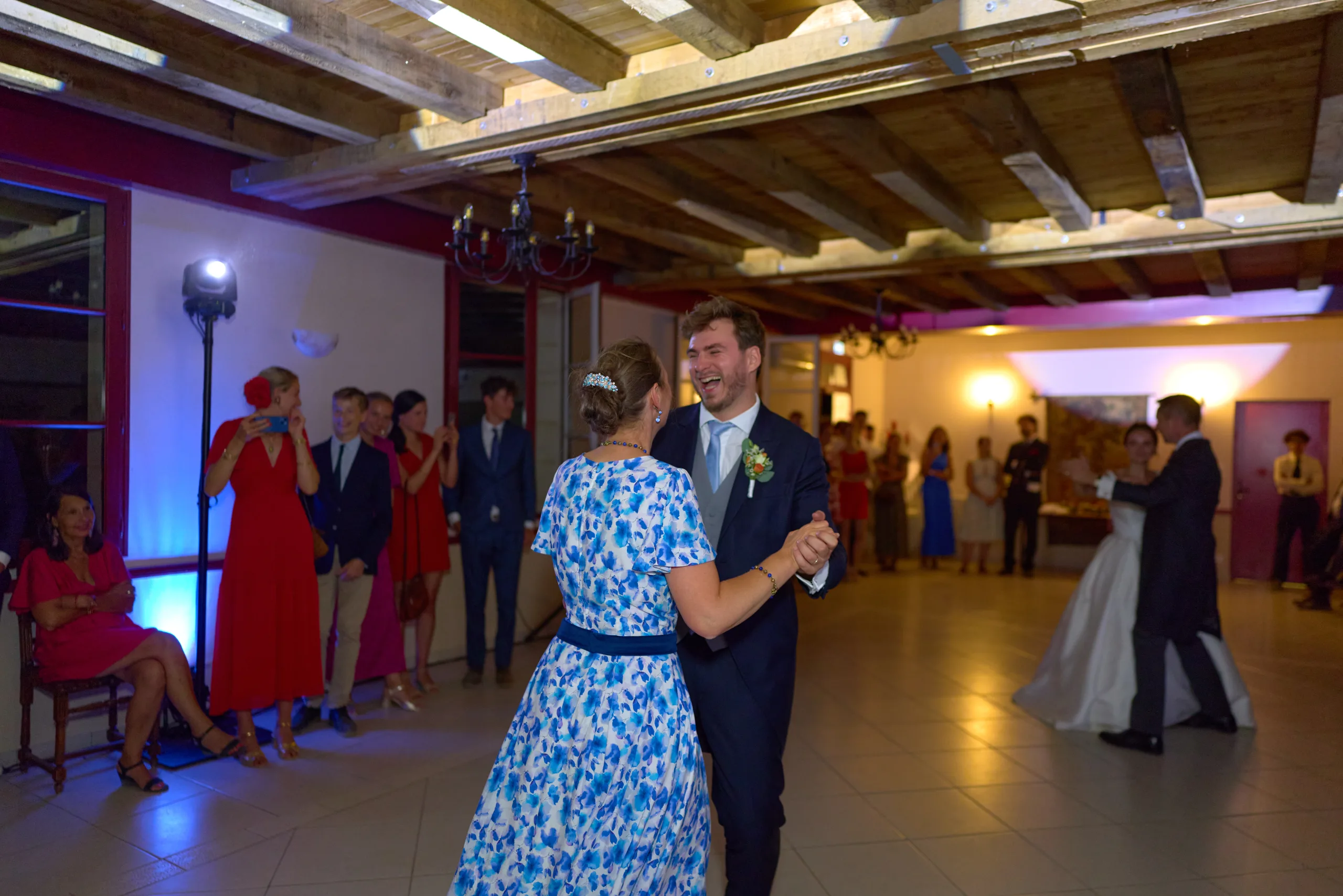 Le marié danse avec une invitée en robe bleue à fleurs